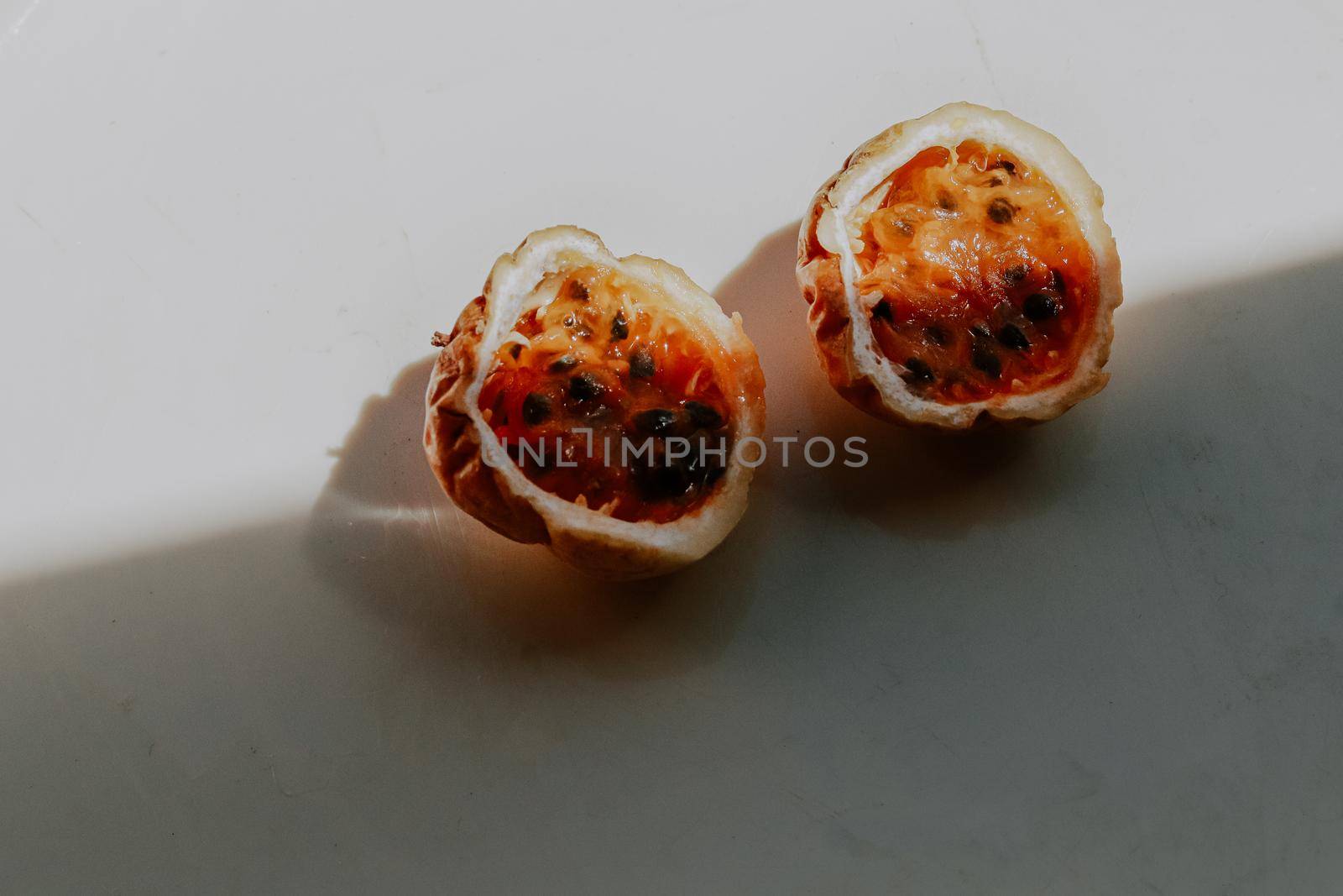 Close up of a yellow passion fruit sliced in half against white background