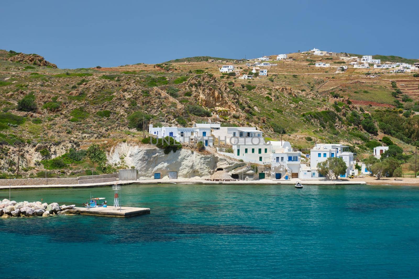 Greek fishing village with traditional whitewashed white houses on Milos island view from Aegean sea in Greece