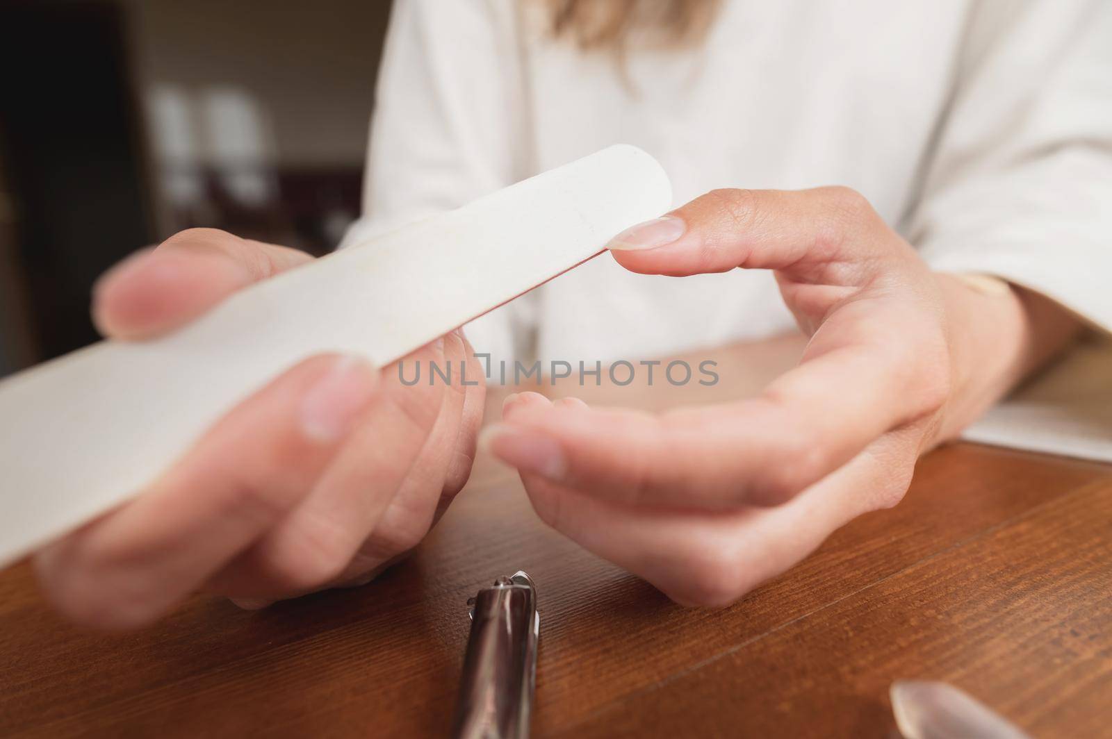 Close-up of hand of caucasian young woman doing manicure at home with nail supplies. by yanik88