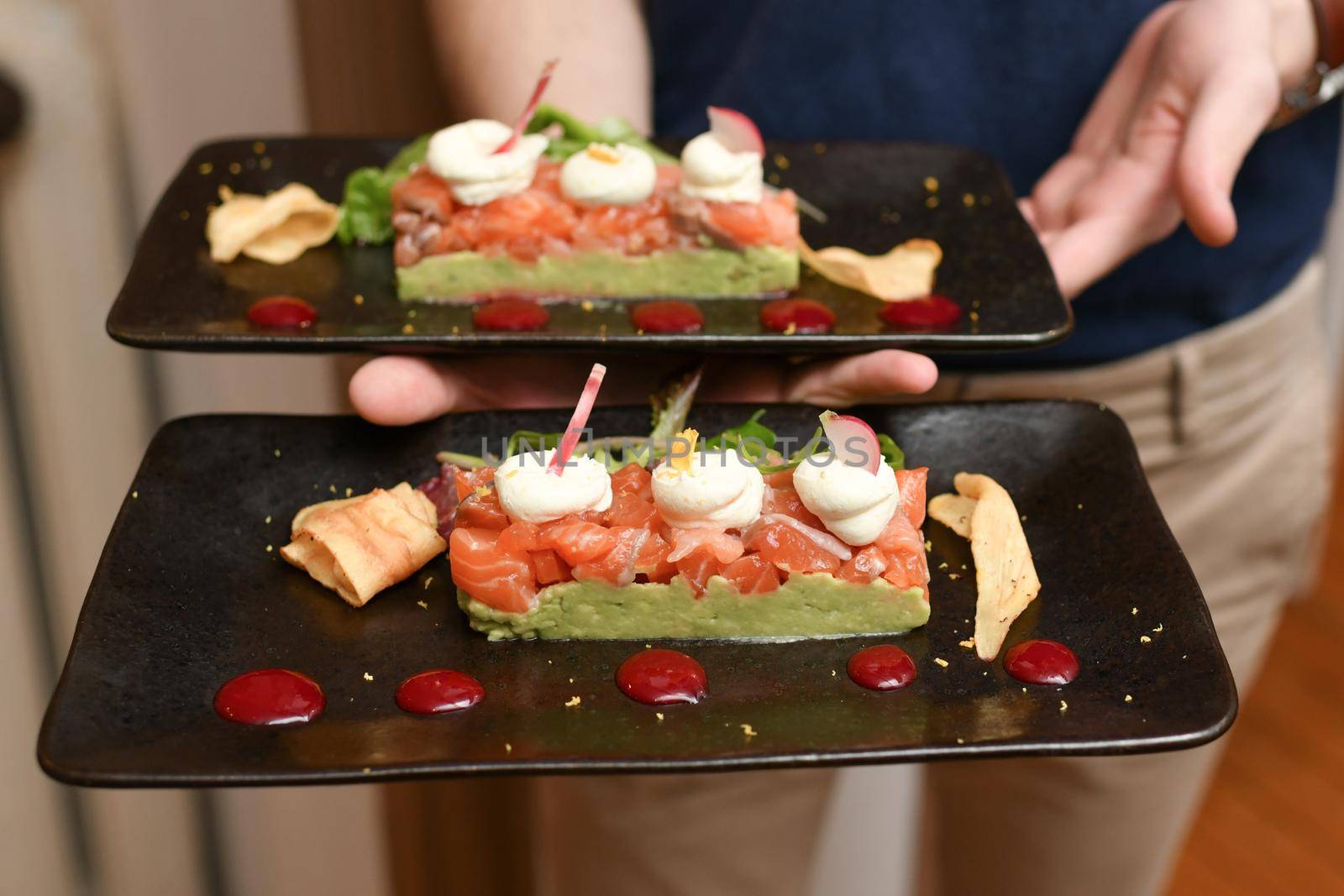 A waiter holding plates of salmon and guacamole