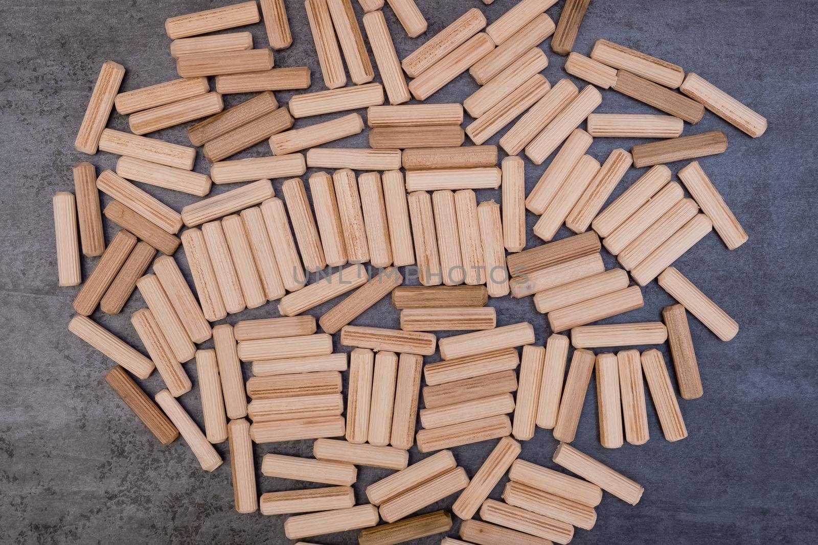 View of a grouping of wooden dowels on grey background. Close-up.