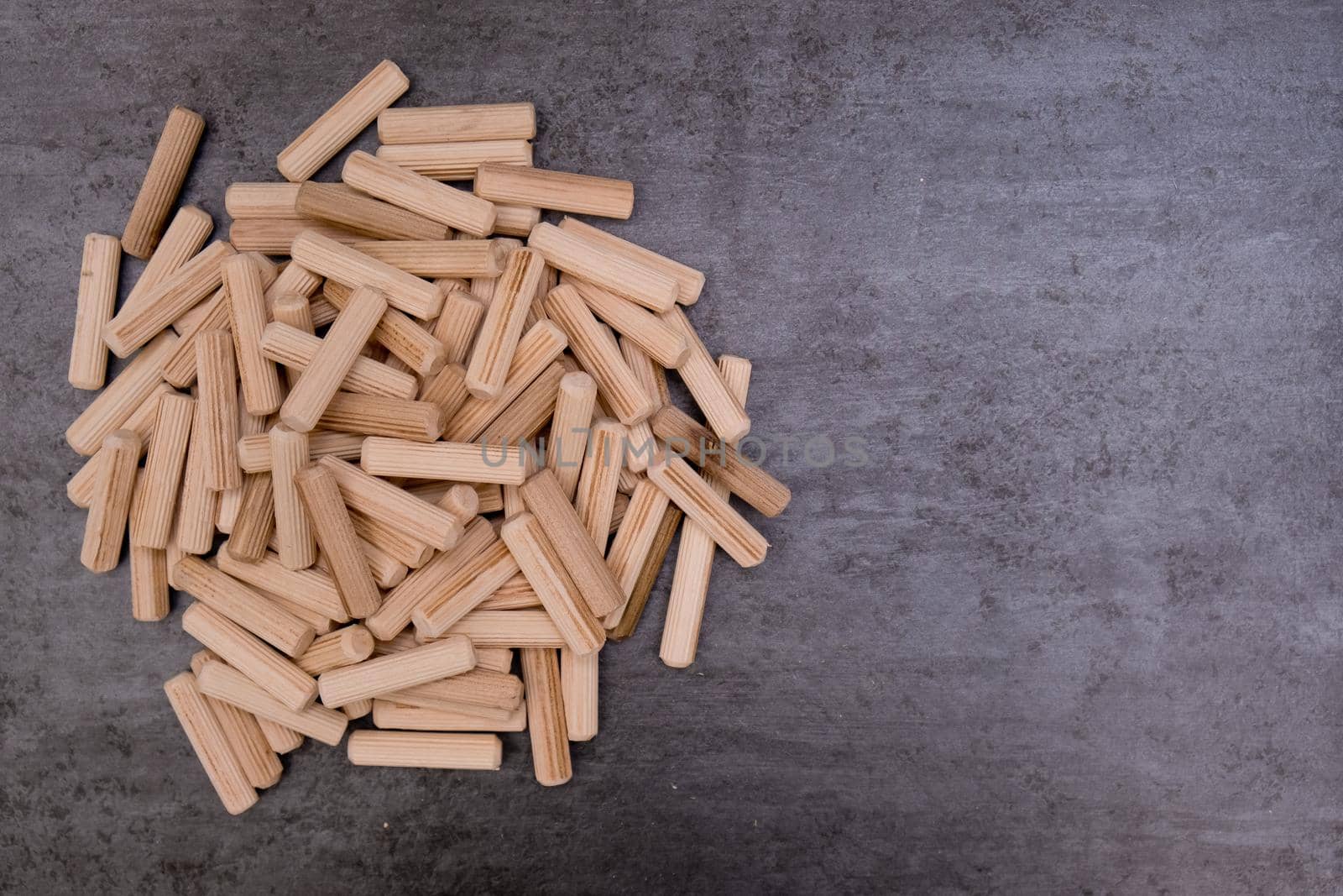 View of a grouping of wooden dowels on grey background. Close-up. Selective focus.