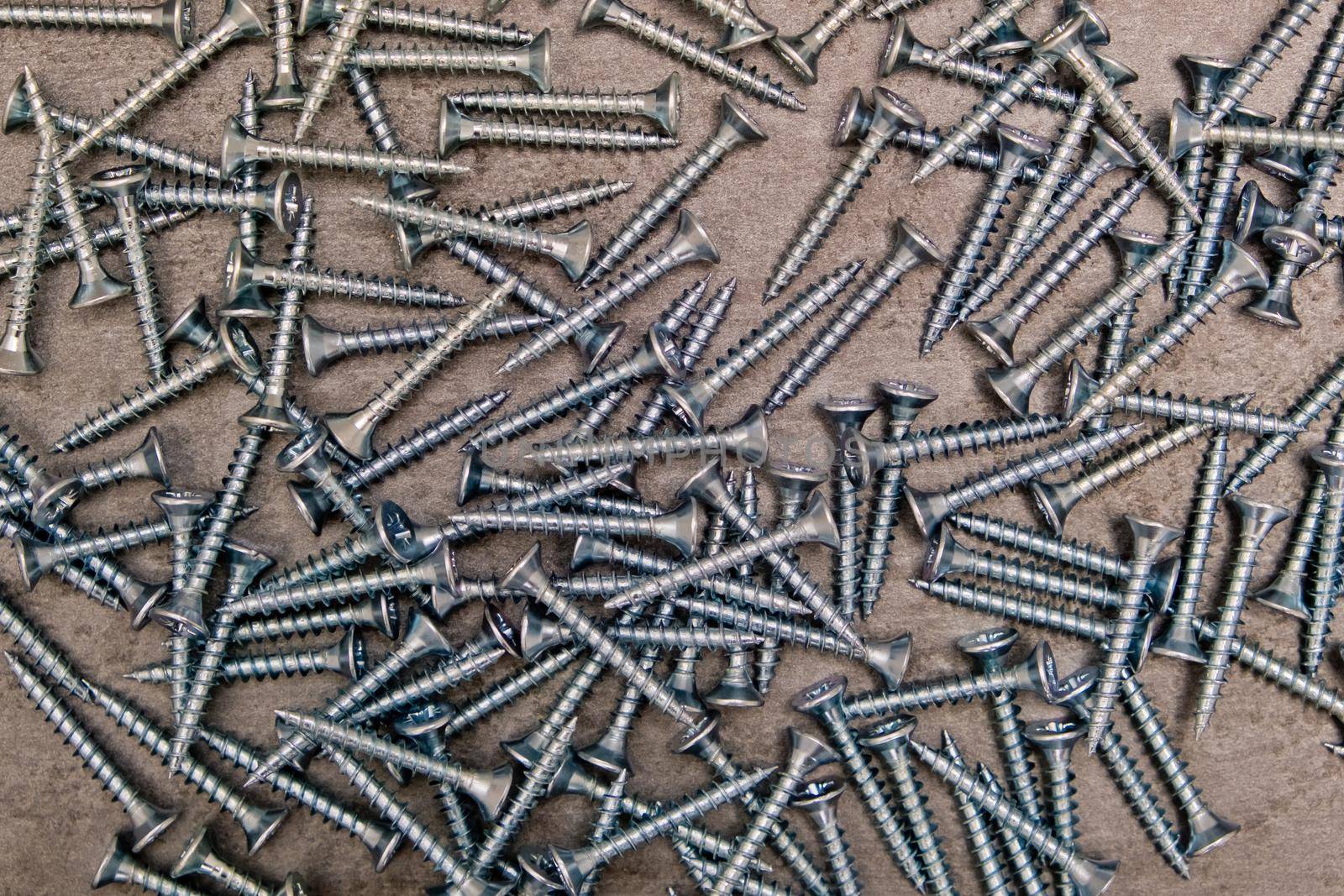 A lot of silver metal screws on the table close-up, background.