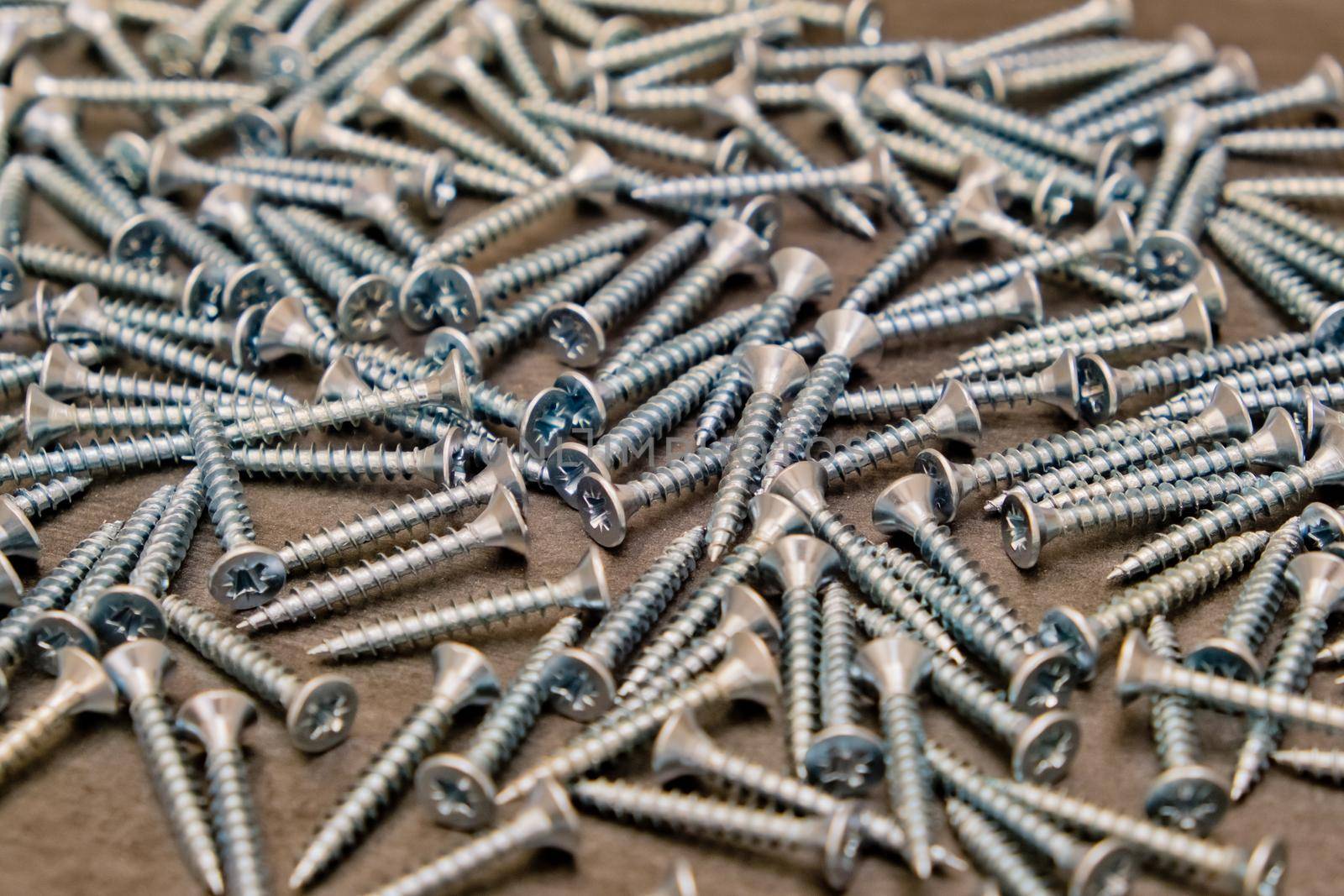 A lot of silver metal screws on the table close-up, background. Selective focus. by leonik