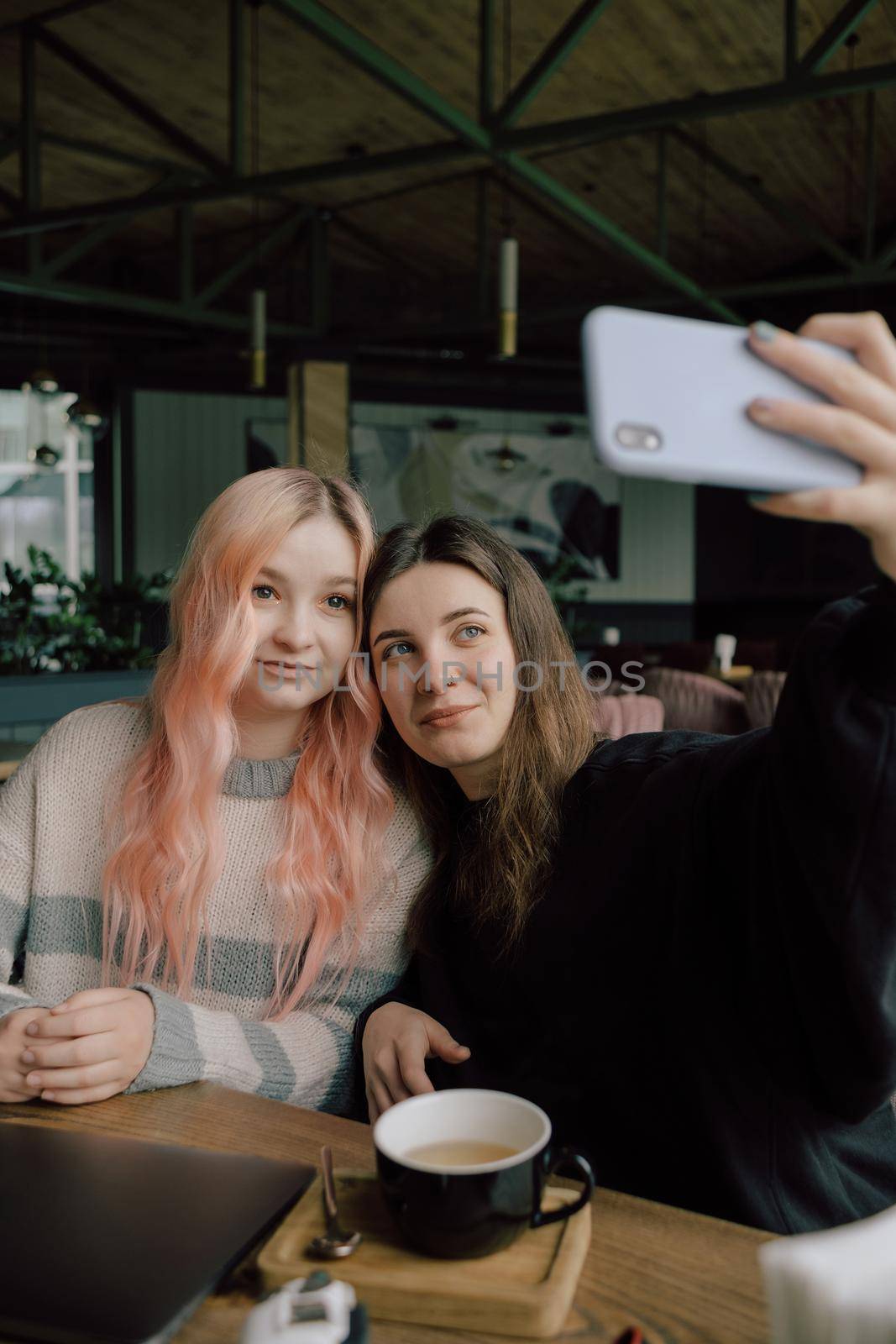 Cheerful young lesbian couple selfie using mobile phone at a coffee shop. Two joyful attractive Asian girls together at restaurant or cafe. Holiday activity, or modern lifestyle concept.