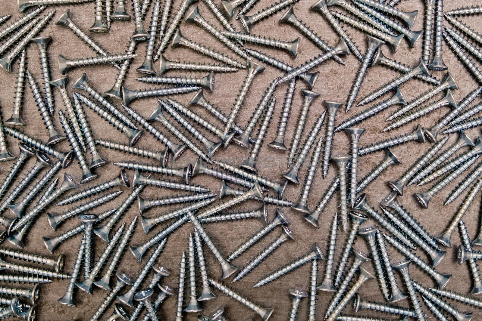 A lot of silver metal screws on the table close-up, background.