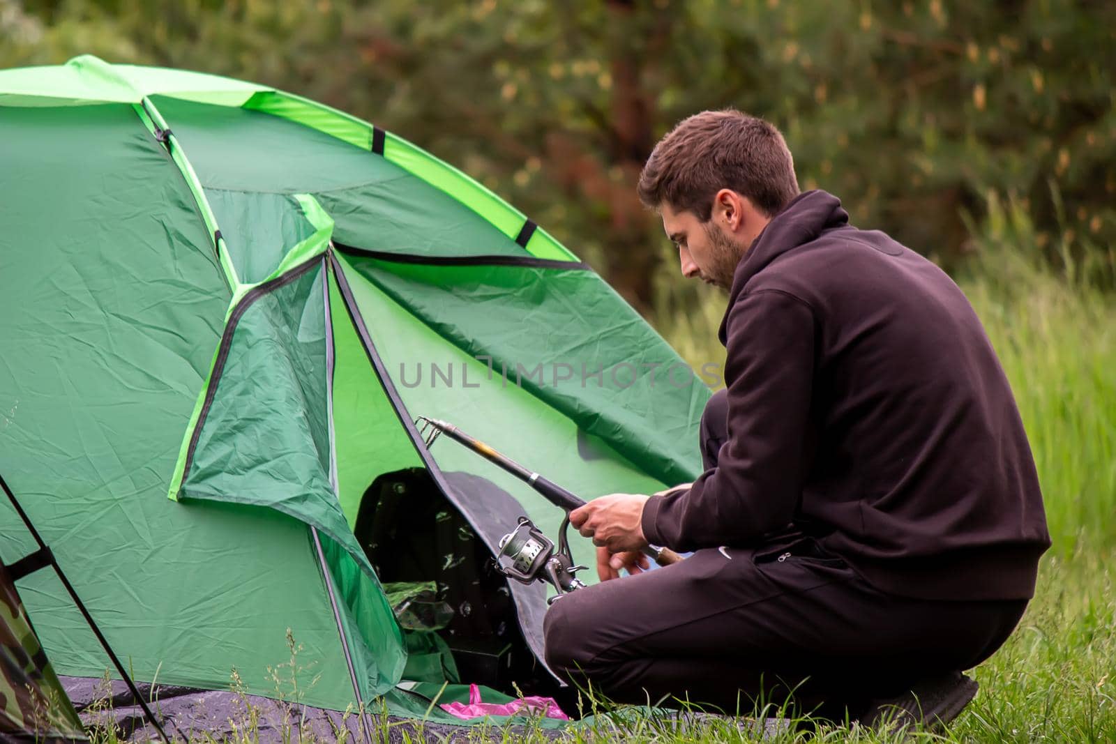a man sits near a tourist tent. Nature, recreation, camping. Selective focus