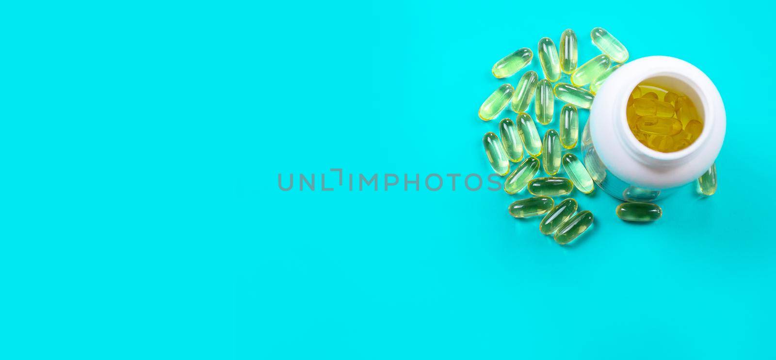 Omega 3 fish oil capsules spilling out of a bottle on a blue background.