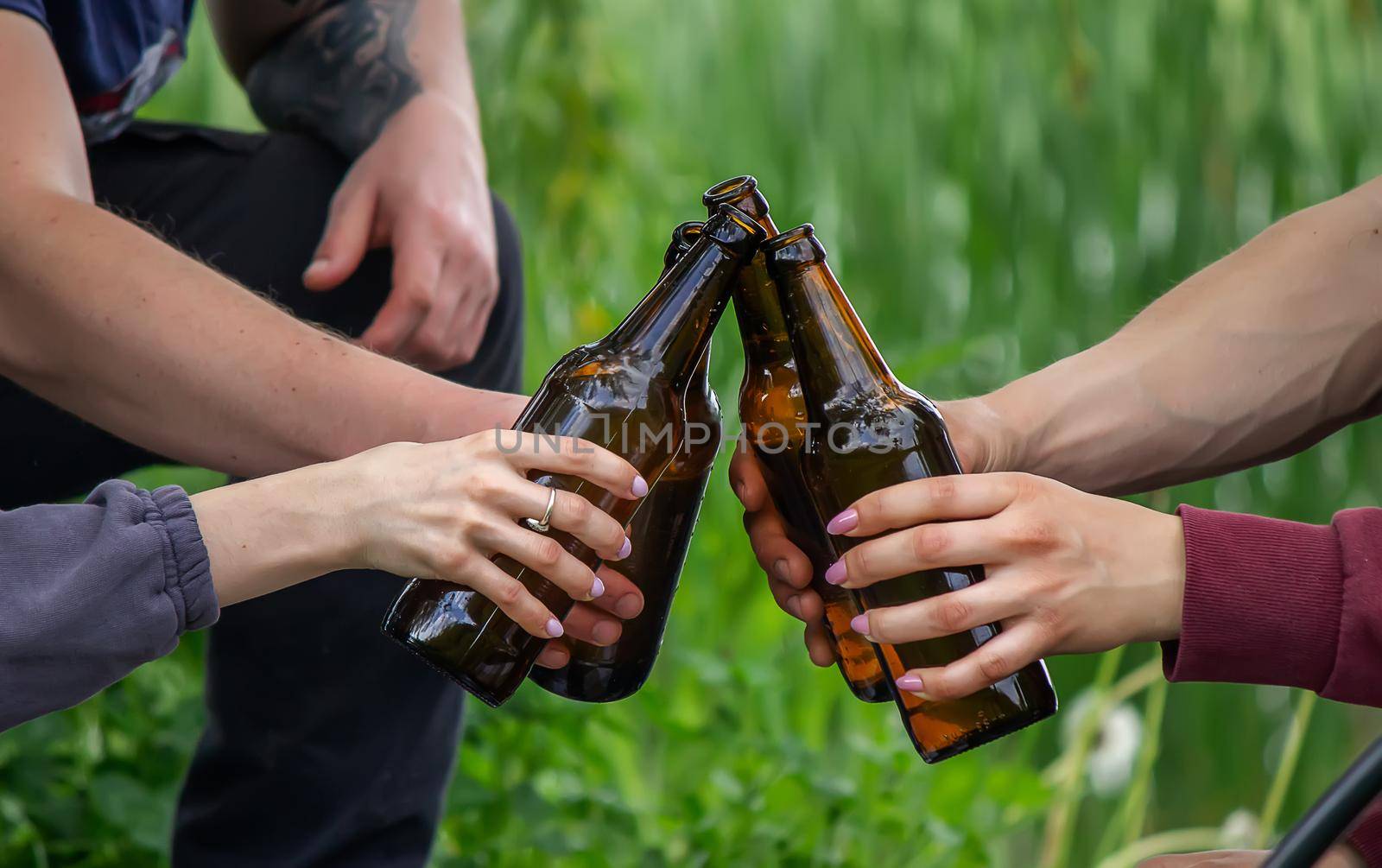The hand of a man holding a beer bottle in nature. rest by the river. Nature. Selective focus