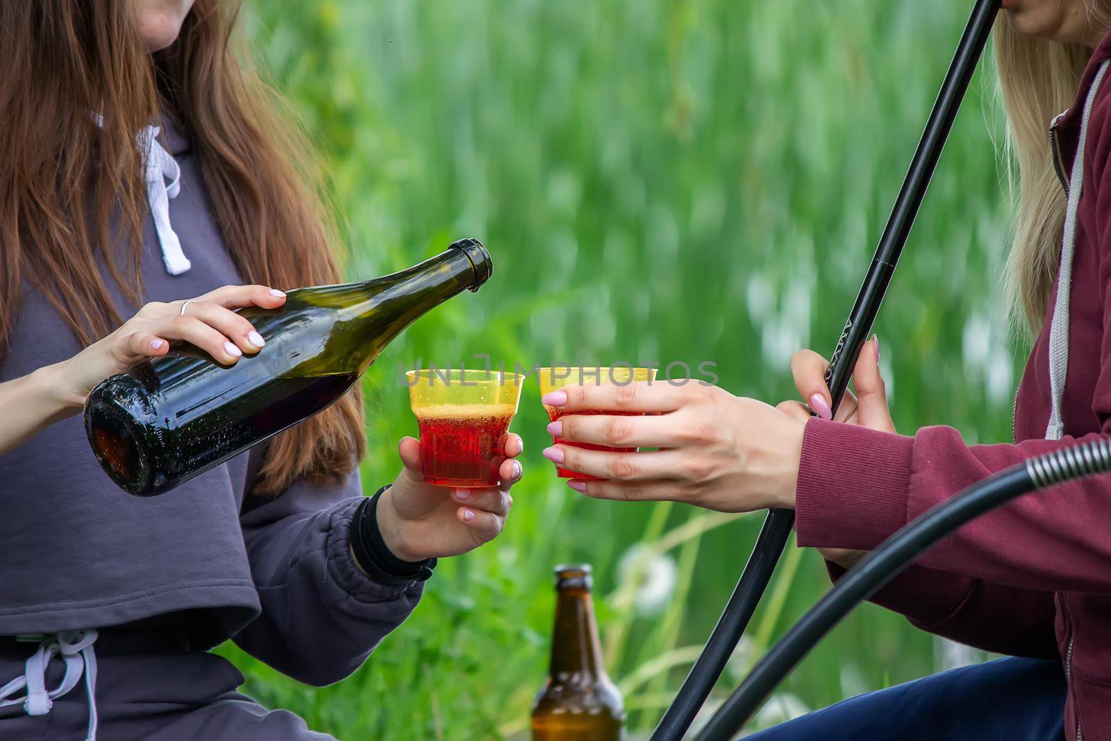 girls drink wine in nature by the river. Selective focus by Anuta23