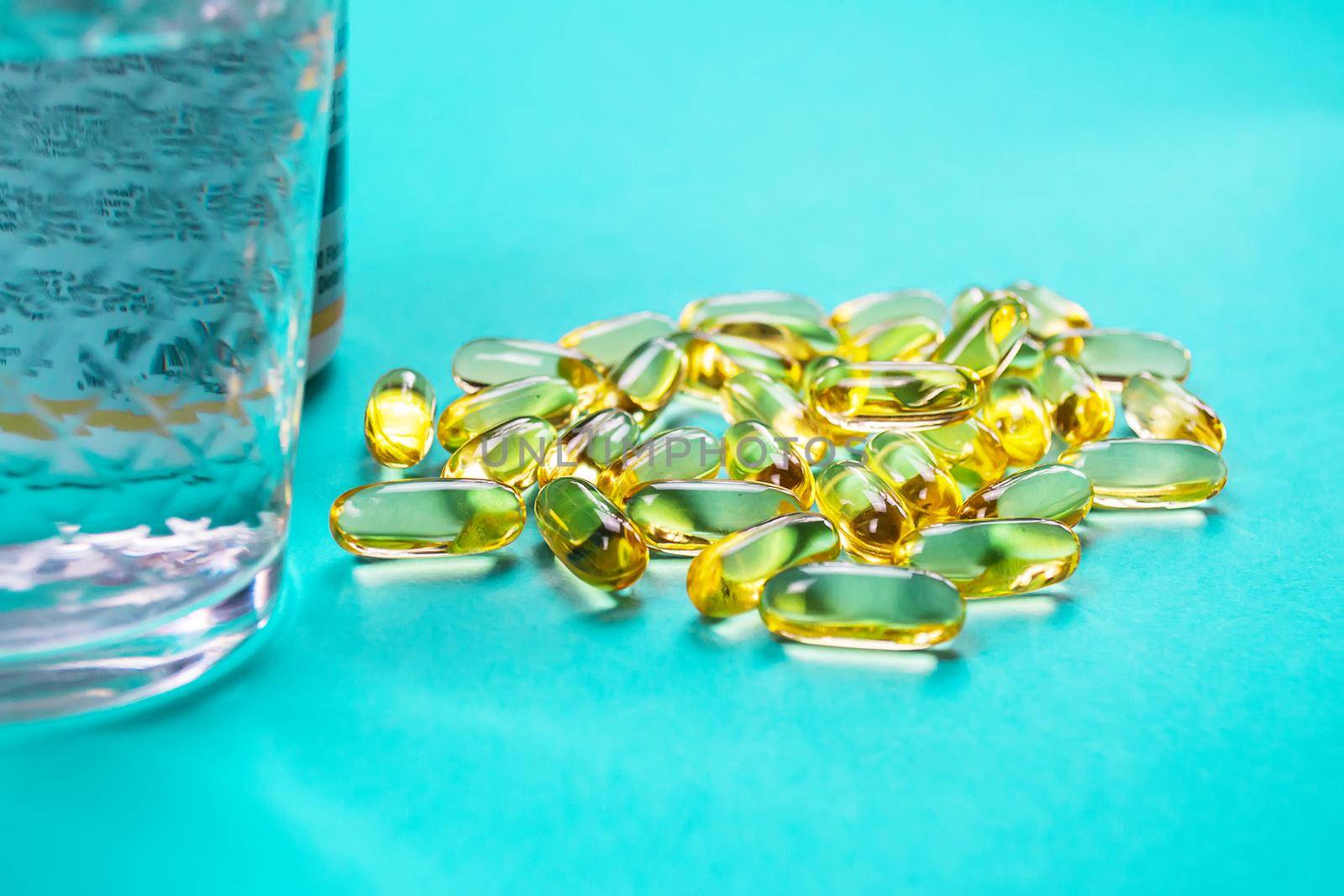 Omega 3 fish oil capsules spilling out of a bottle on a blue background.