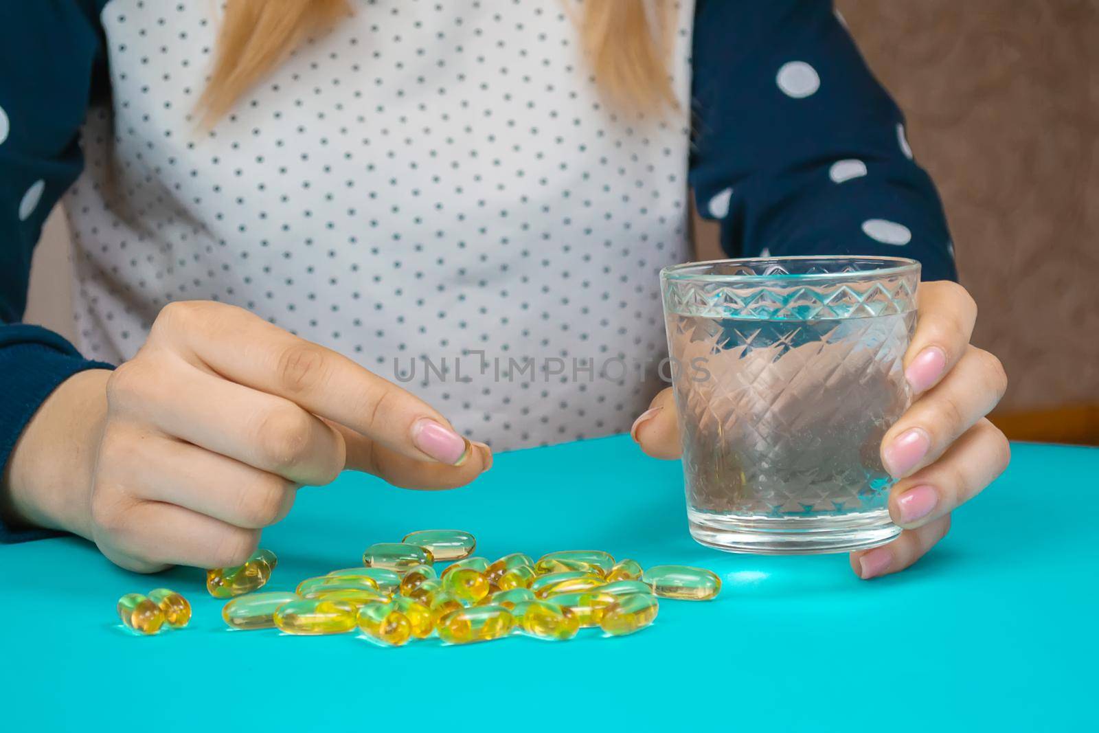 Omega 3 fish oil capsules spilling out of a bottle on a blue background.