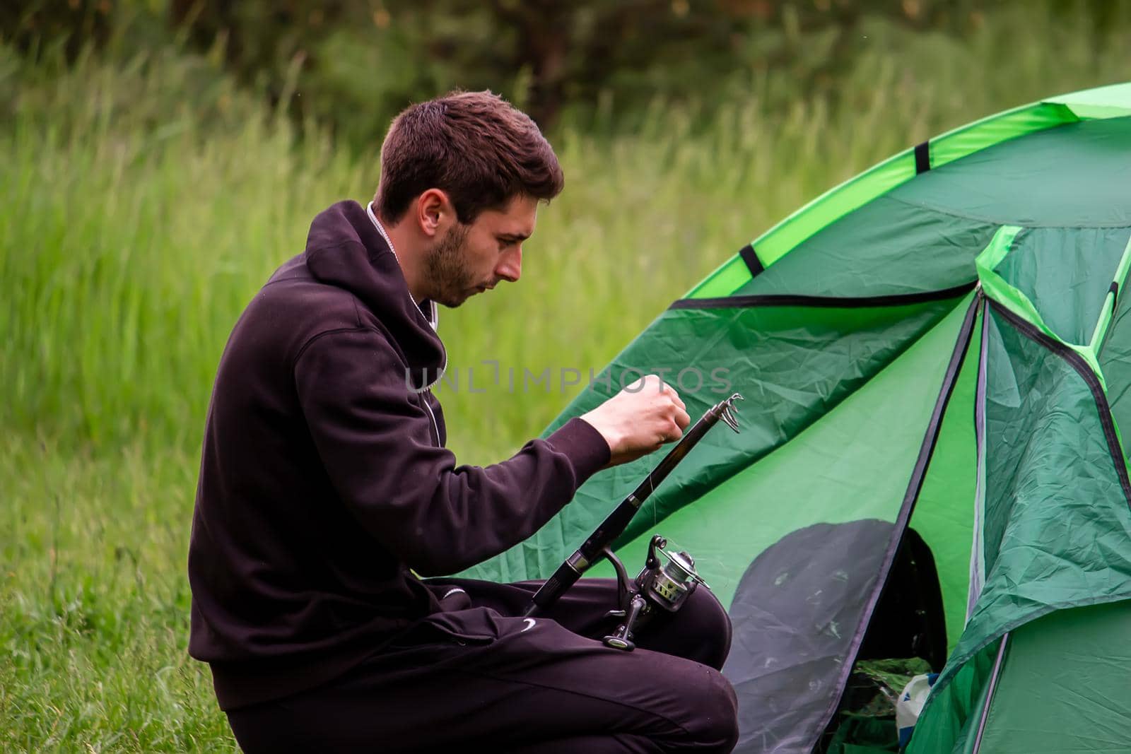 a man sits near a tourist tent. Nature, recreation, camping. by Anuta23