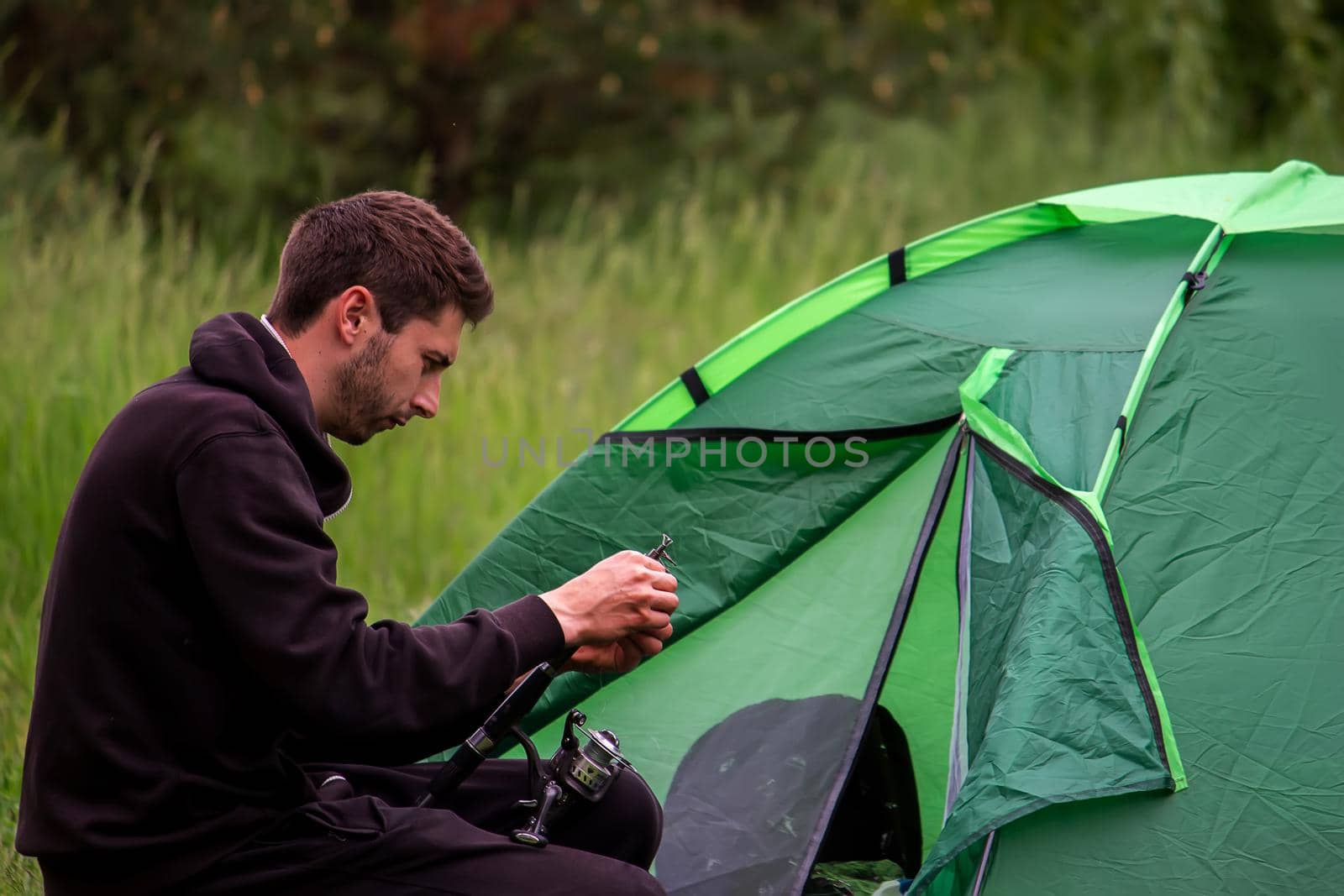 a man sits near a tourist tent. Nature, recreation, camping. by Anuta23