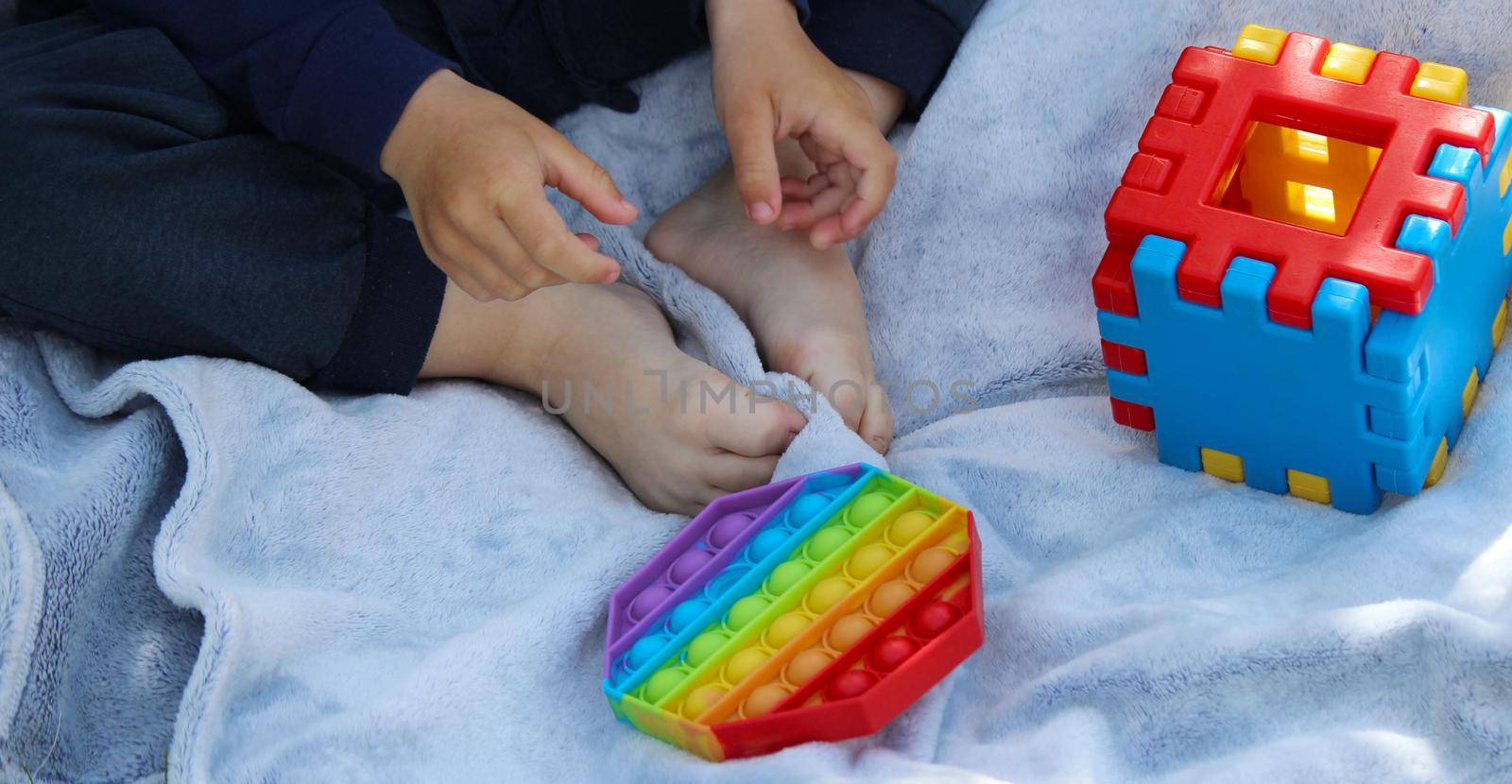 Pop it silicone anti-stress toy. The child plays on the grass. New trend Selective focus. Nature