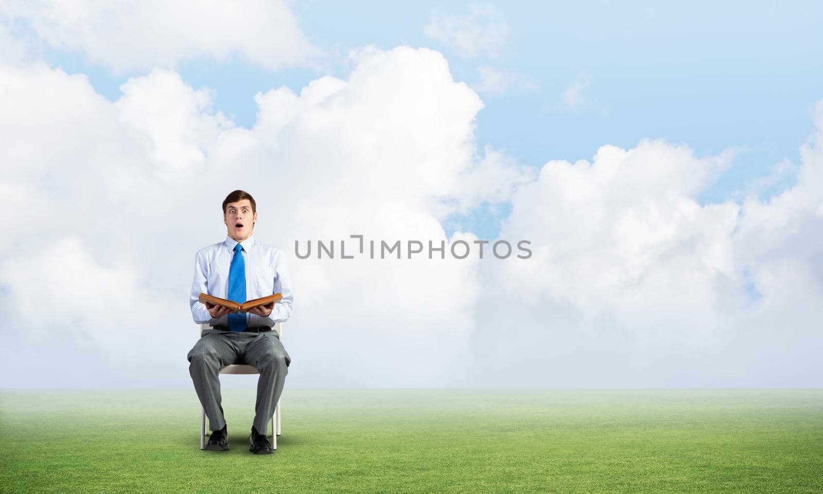 young businessman with book on office chair