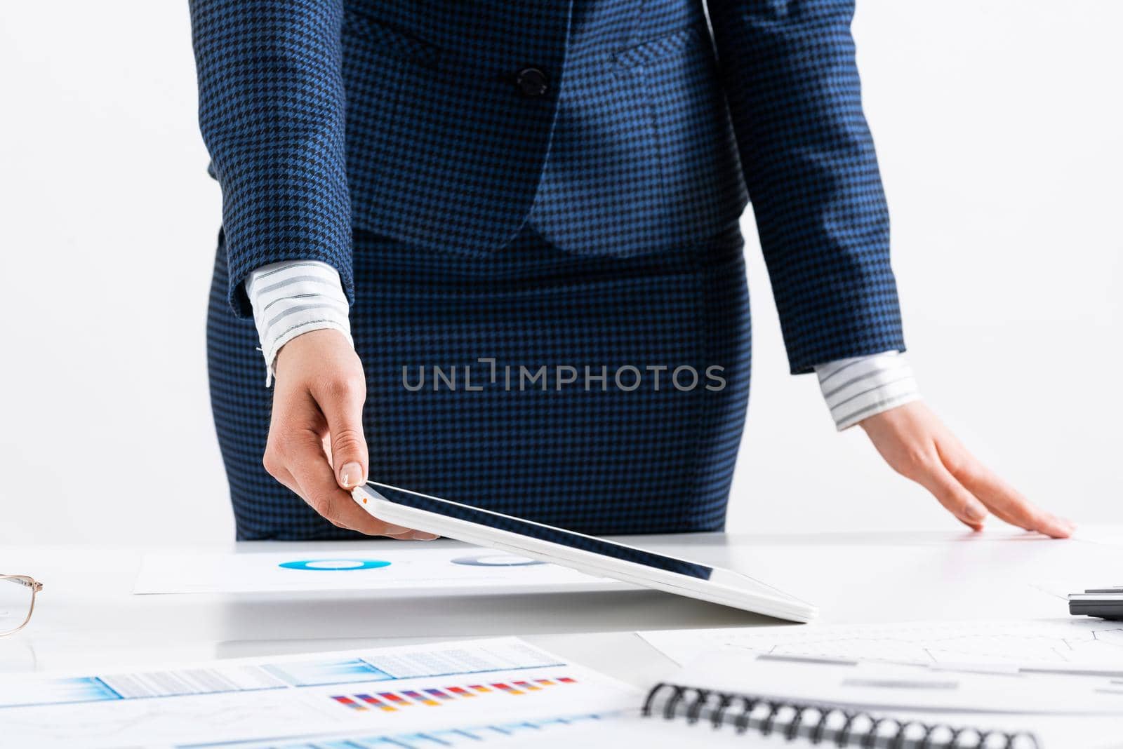 Businesswoman standing near office desk and using tablet computer. Banking and financial management. Corporate manager in suit working with online business analytics. Digital technology in business