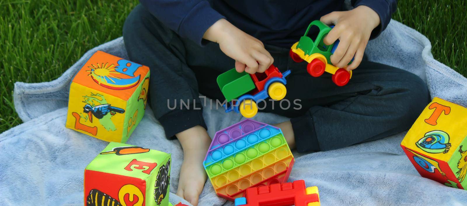Pop it silicone anti-stress toy. The child plays on the grass. New trend Selective focus. Nature