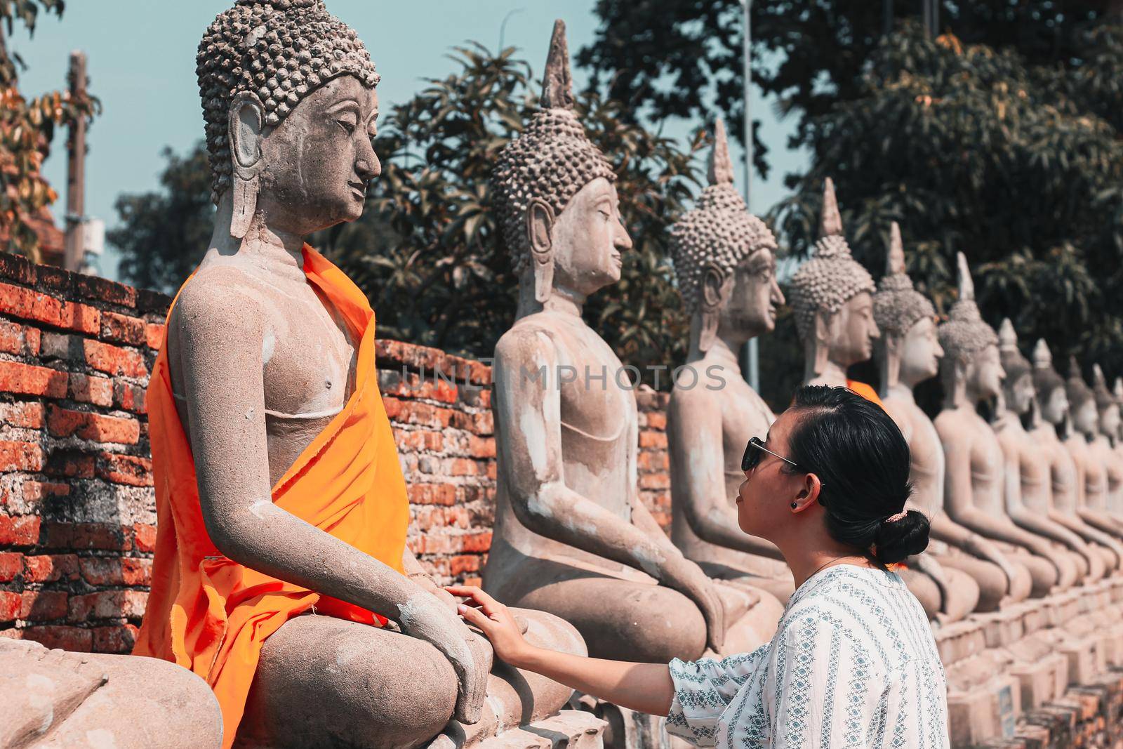 Asian girl exploring the row of Buddha statues at Wat Yai Chai Mongkhon temple in Ayutthaya, Thailand