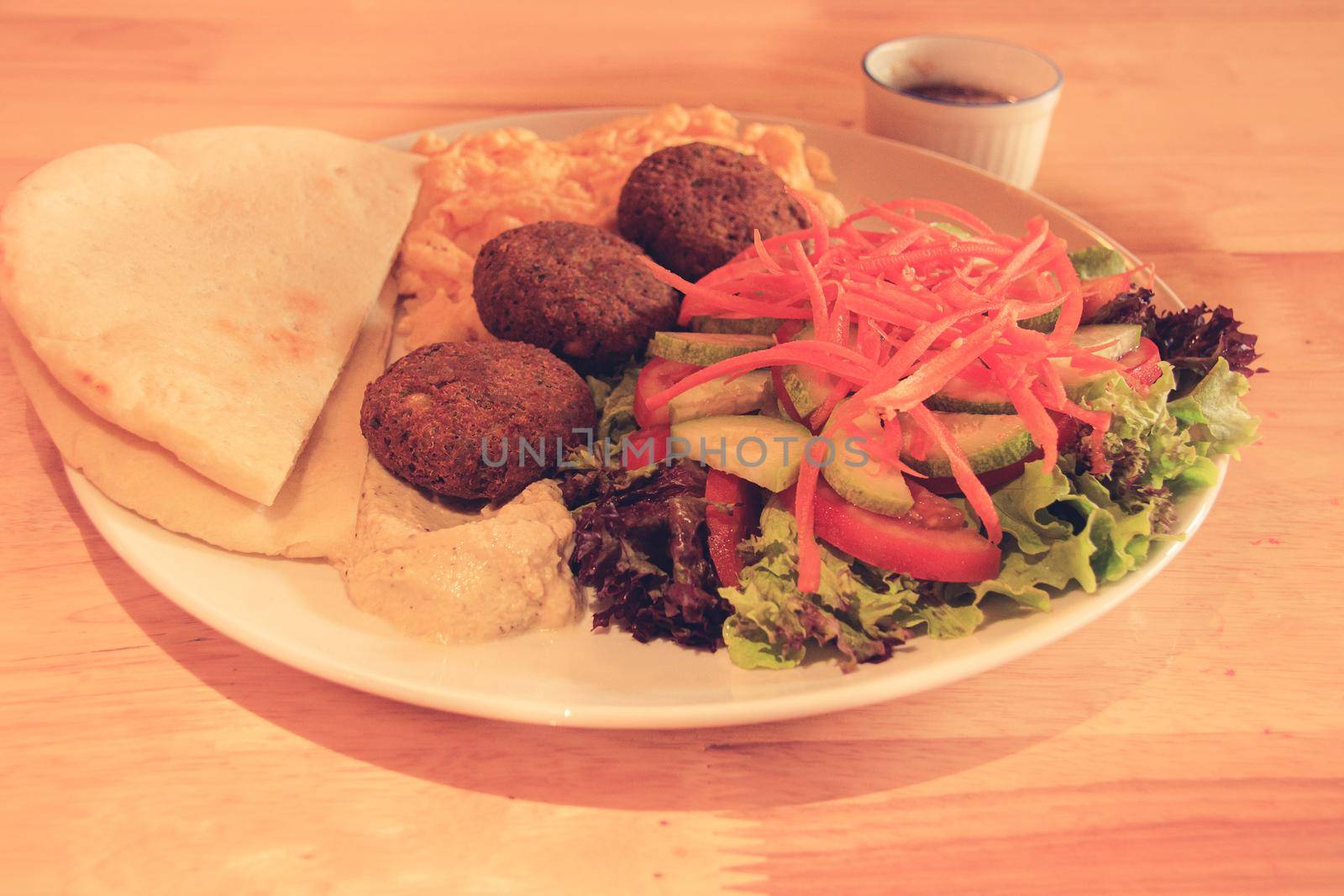 A plate full of falafel balls, pita bread, scrambled eggs and raw vegetable salad by Sonnet15