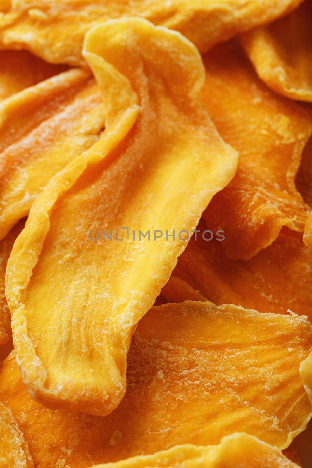 Dried sweet mango fruit slices as textural orange background in full screen