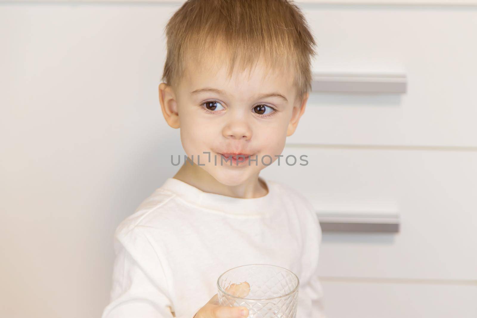 The child drinks water from a glass. Selective focus.