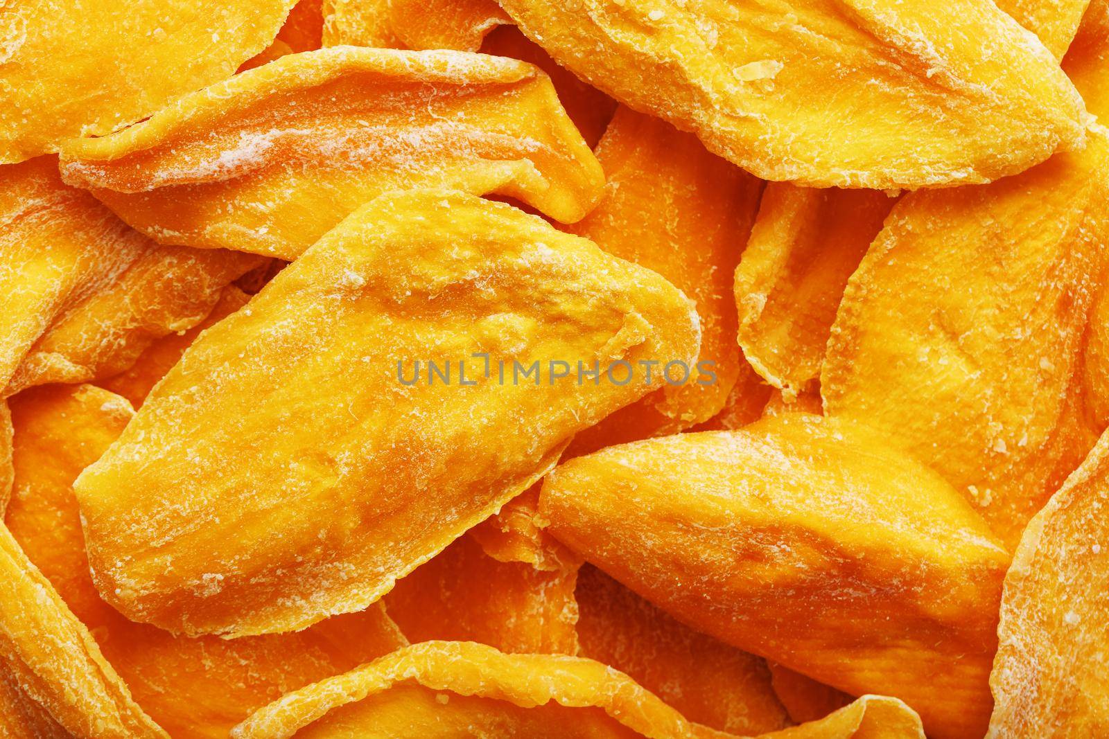 Dried sweet mango fruit slices as textural orange background in full screen