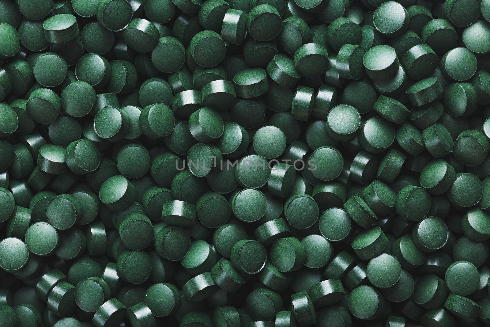 Dark Green round tablets of organic spirulina as a texture background in full screen