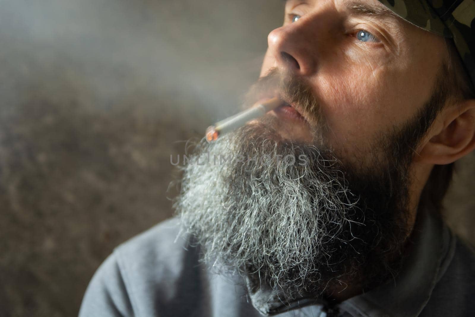 The man with the long beard is smoking a cigarette, portrait