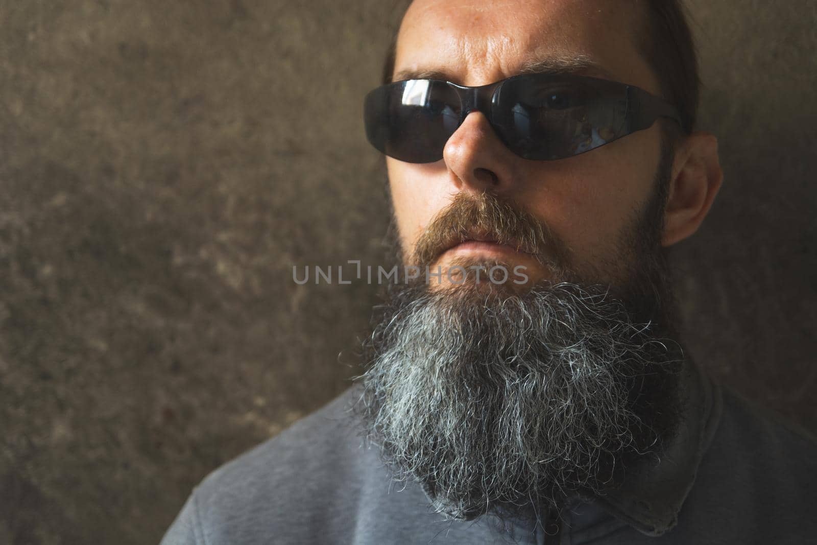 A man with a long beard on the background of the dark wall