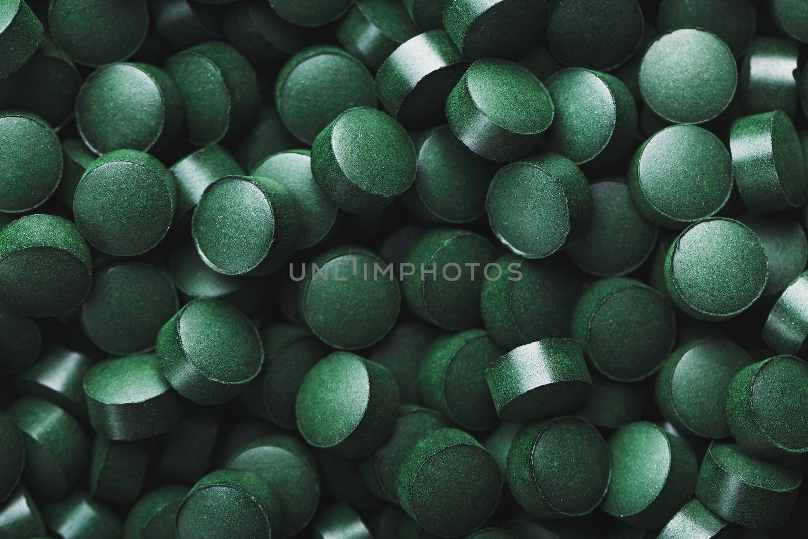 Dark Green round tablets of organic spirulina as a texture background in full screen