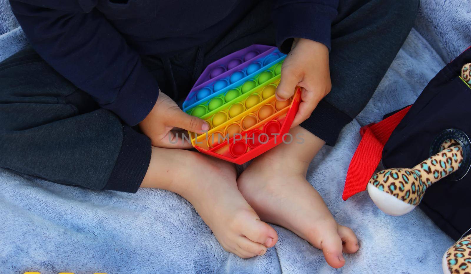 Pop it silicone anti-stress toy. The child plays on the grass. New trend Selective focus. Nature