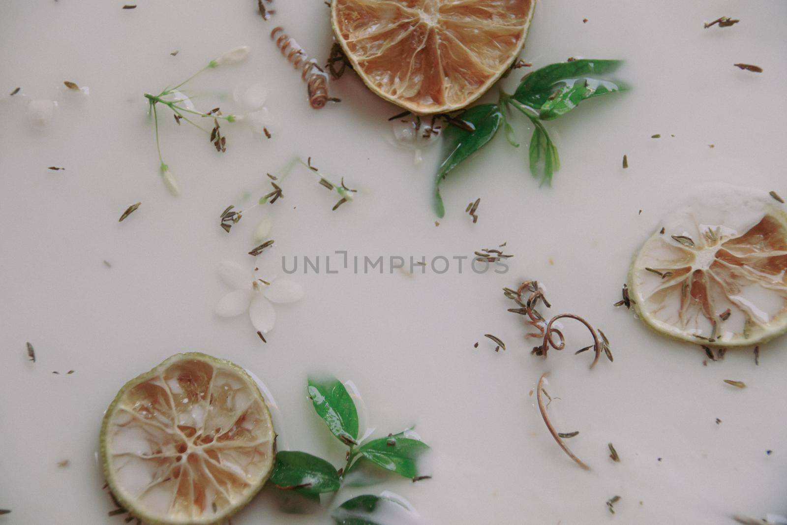 Close up of a therapeutic milk bath filled with dried lemon slices by Sonnet15