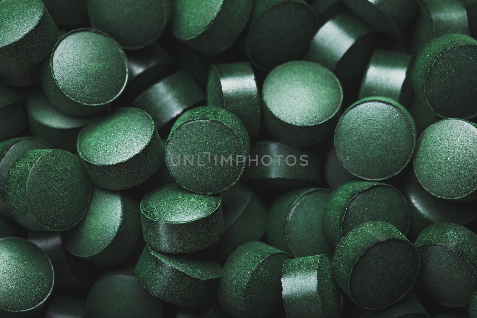 Dark Green round tablets of organic spirulina as a texture background in full screen