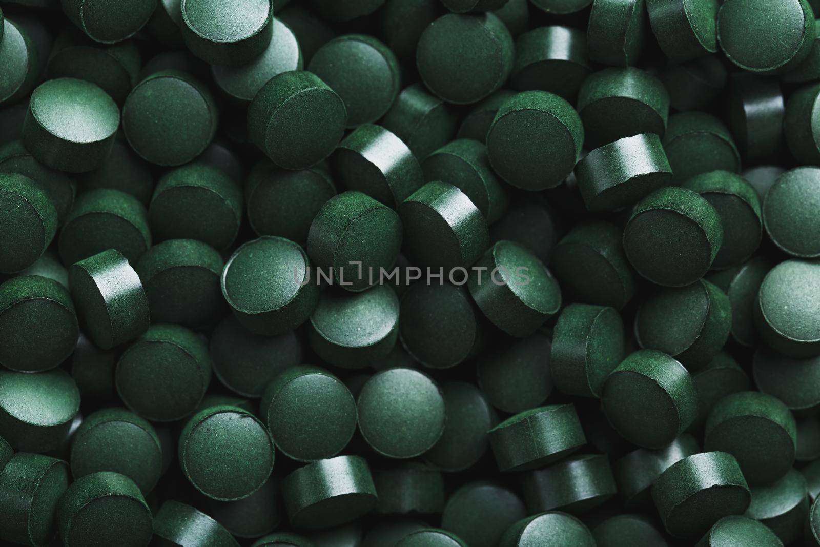 Dark Green round tablets of organic spirulina as a texture background in full screen