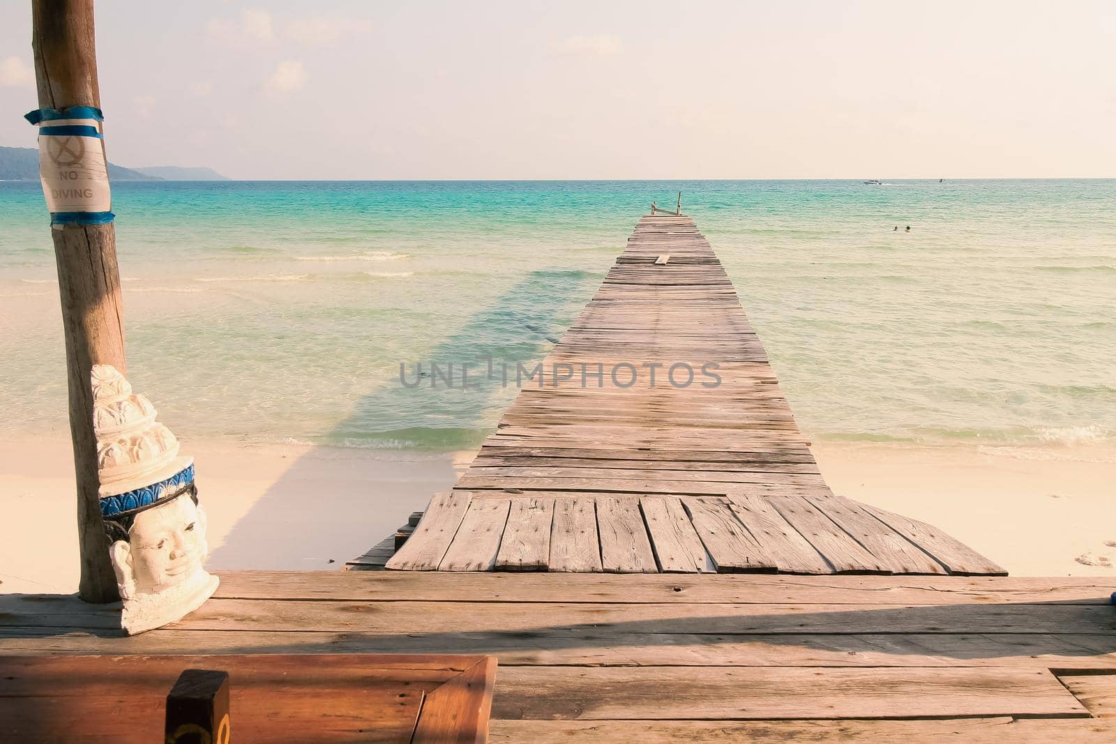 Scenic view of a wooden boardwalk leading to the white sandy beach of Koh Rong Samloen Island, a popular summer getaway destination in Cambodia