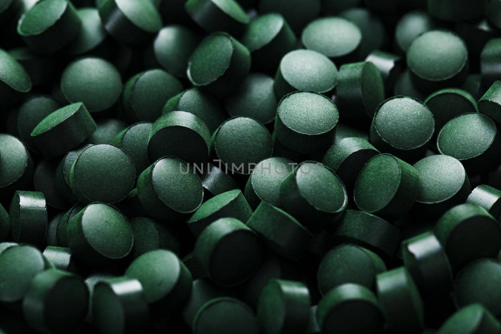 Dark Green round tablets of organic spirulina as a texture background in full screen