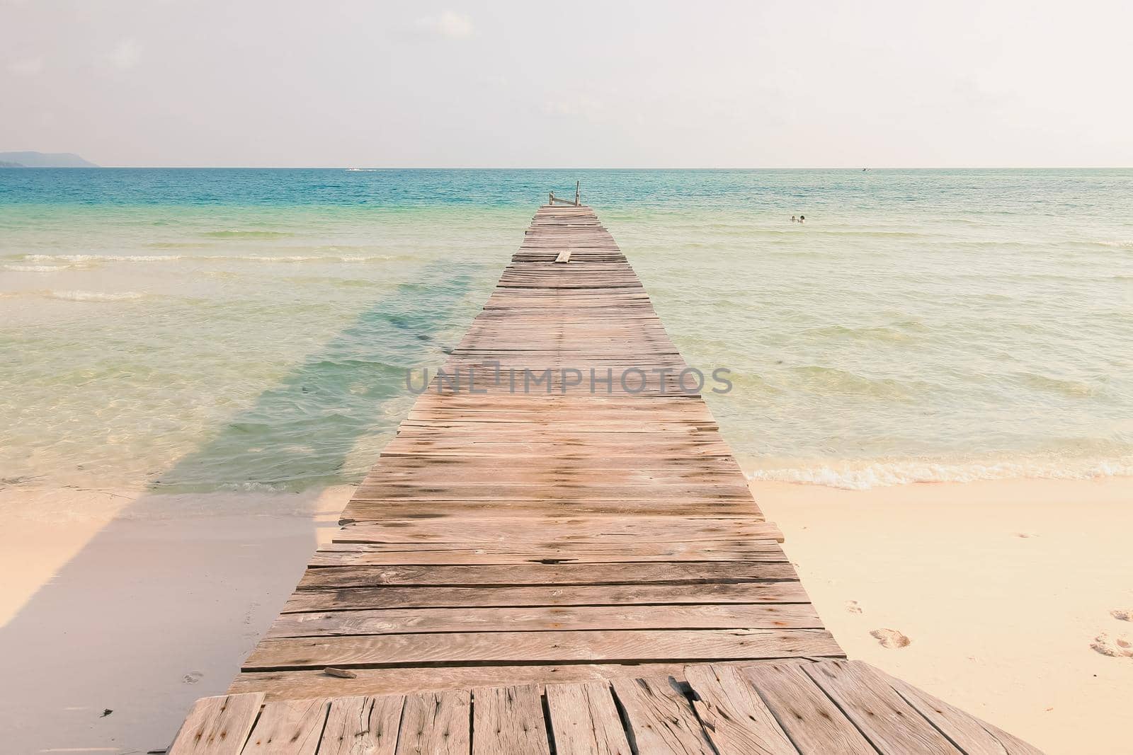 Scenic view of a wooden boardwalk leading to the white sandy beach of Koh Rong Samloen Island, a popular summer getaway destination in Cambodia