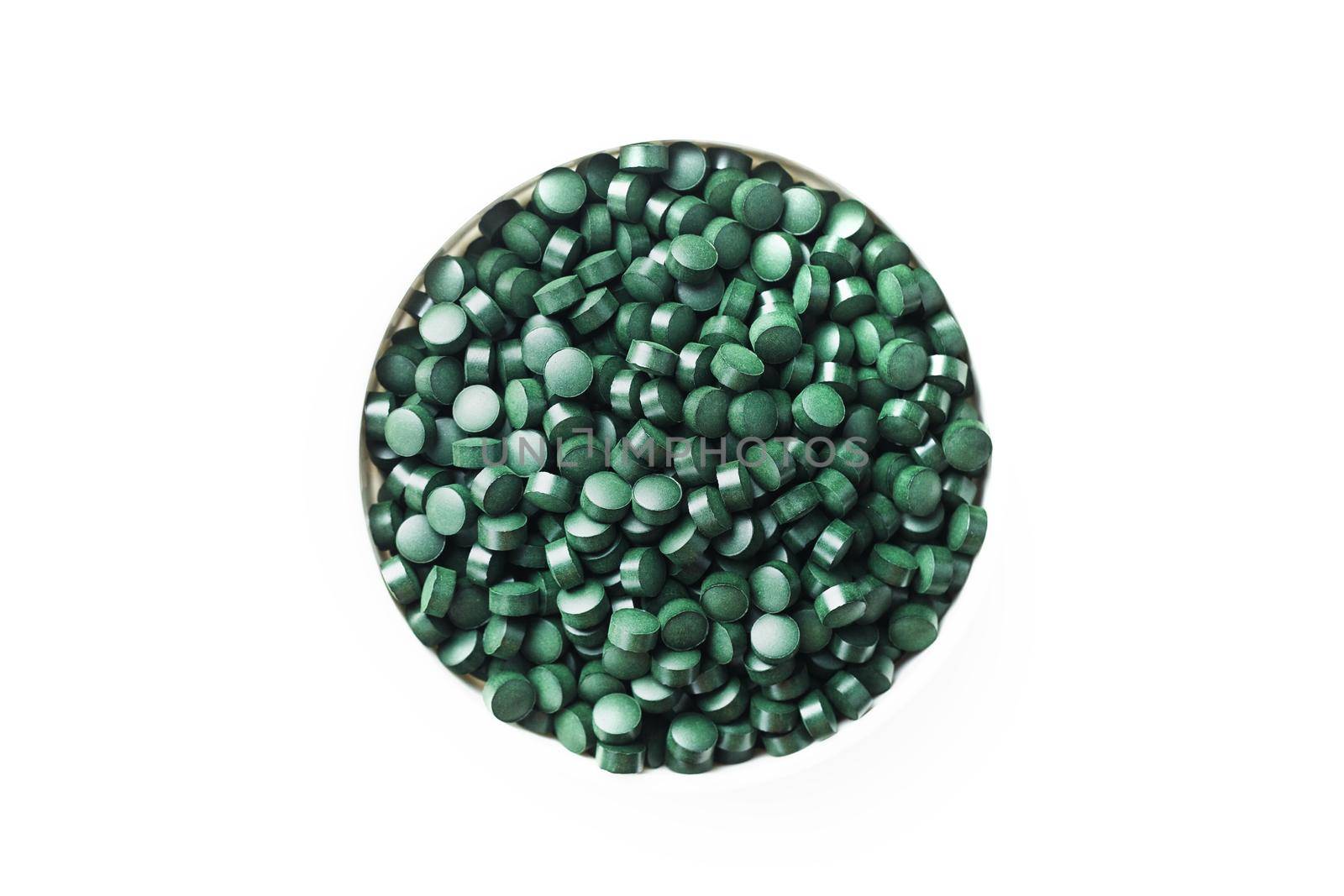 spirulina and chlorella tablets on the light background. green tablets in the small bawl