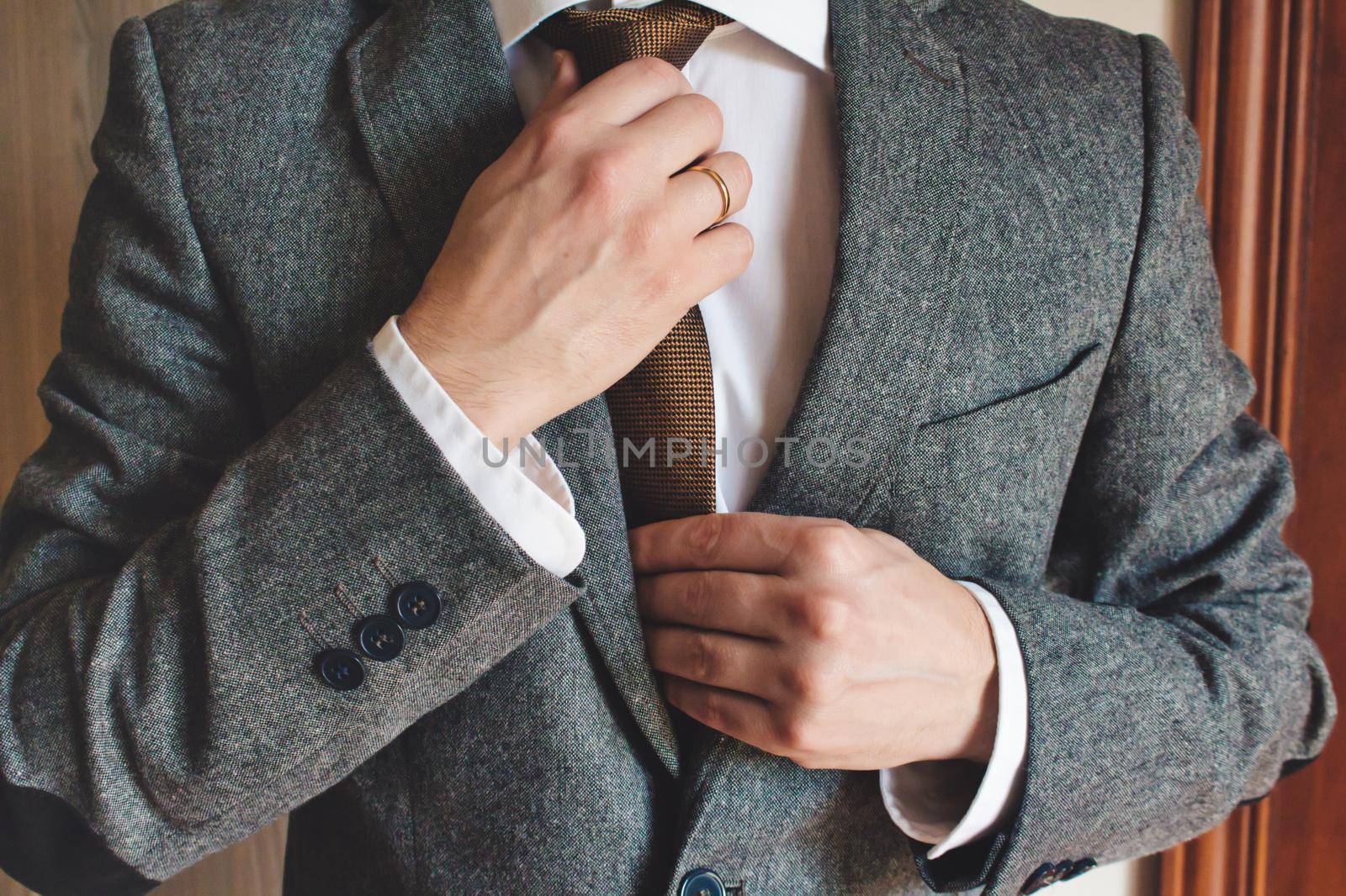 Man in smart suit wearing wedding ring adjusting tie by tennesseewitney