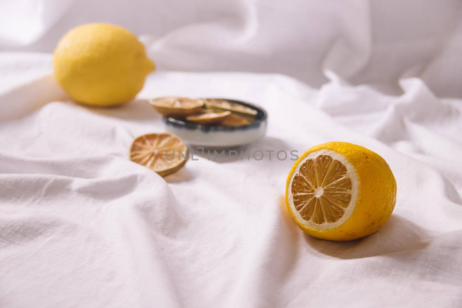 Yellow lemons and dried fruit slices on a bright white background showing the delicate April Spring time aesthetics and sustainable living concept