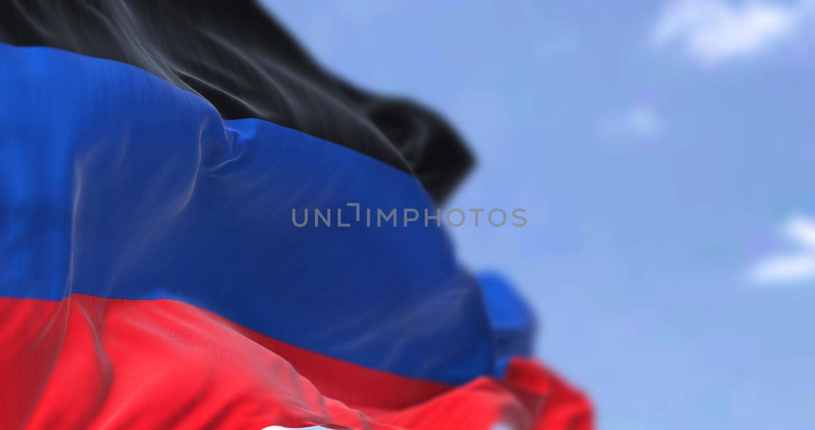 Detail of the national flag of Donetsk People's Republic waving in the wind on a clear day. Donetsk People's Republic is a self-proclaimed breakaway state located in Ukraine. Selective focus.