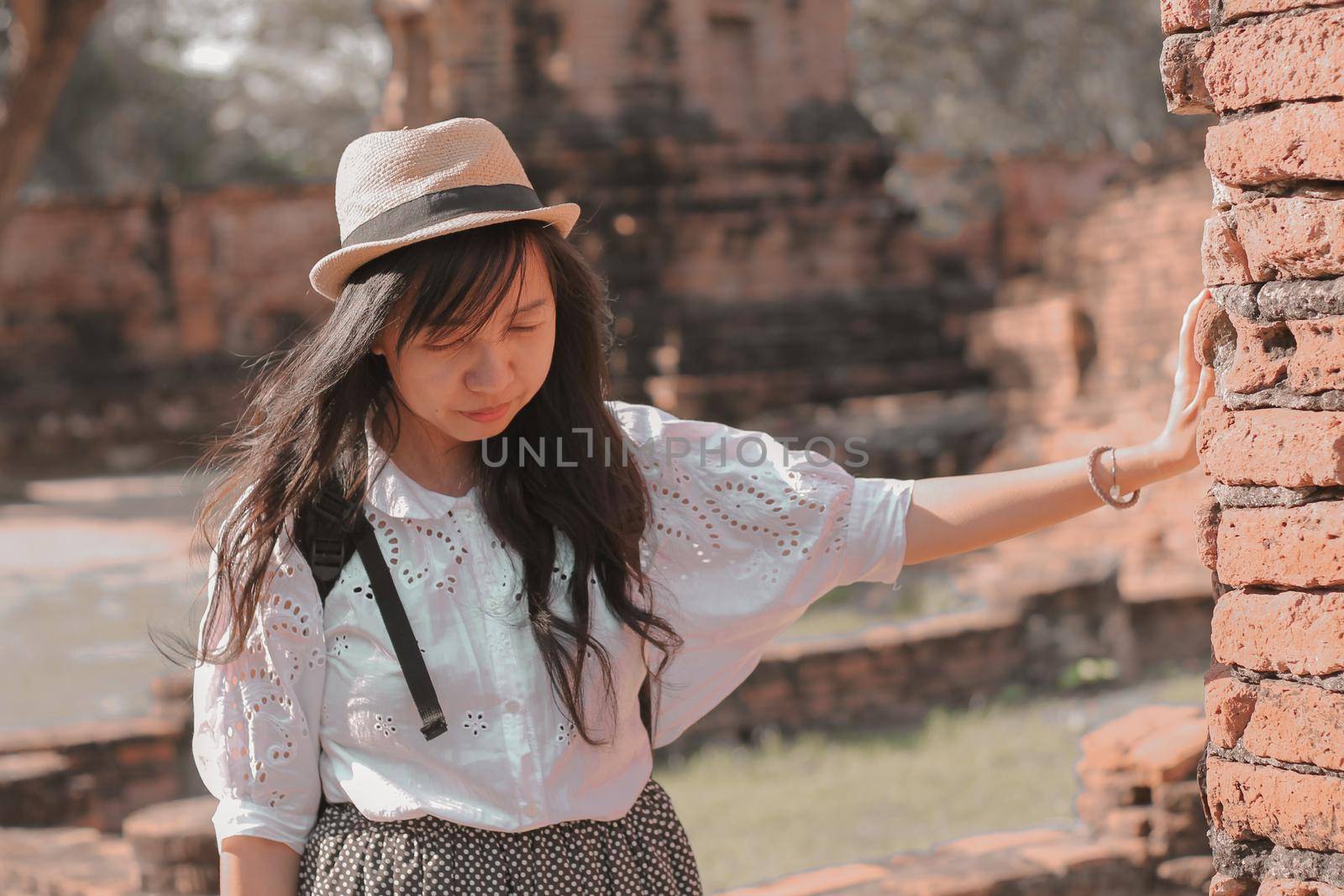 Smiling asian girl exploring the old ruins in Wat Mahathat inside the famous heritage site of Ayutthaya Historical Park in Thailand