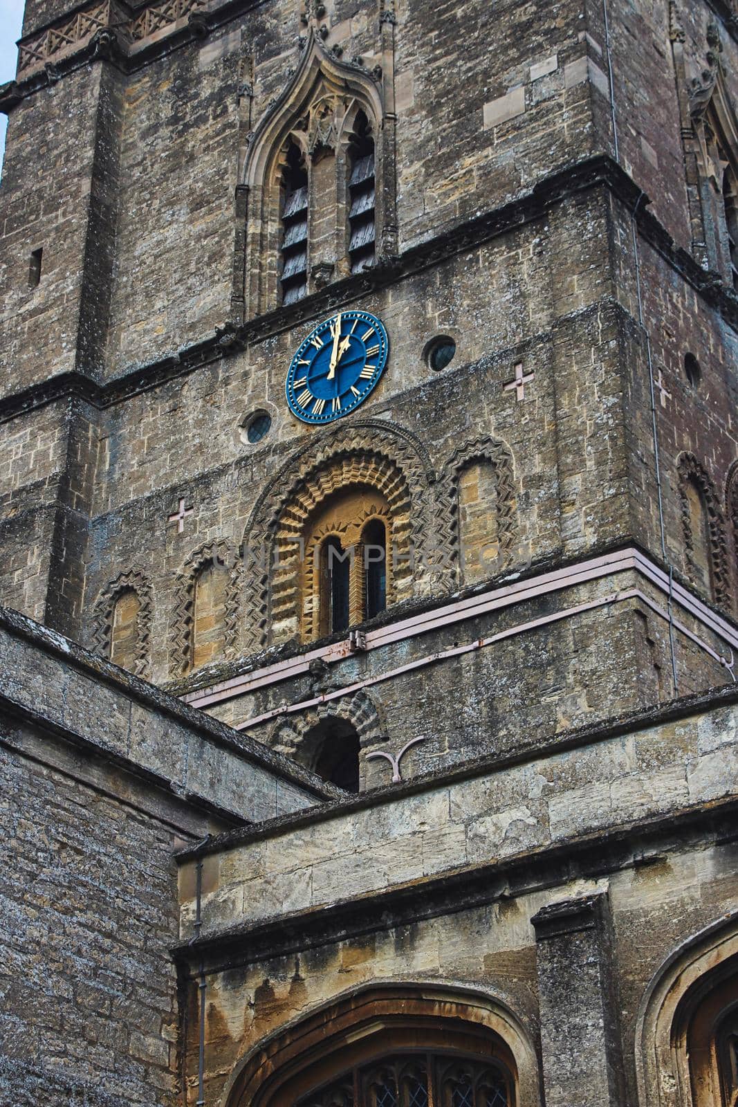 Church clock tower with blue clock face in the classic style in England