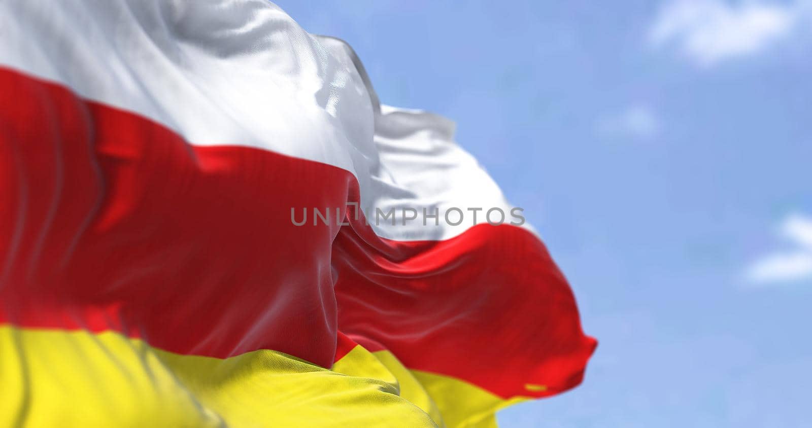 Detail of the national flag of South Ossetia waving in the wind on a clear day. by rarrarorro