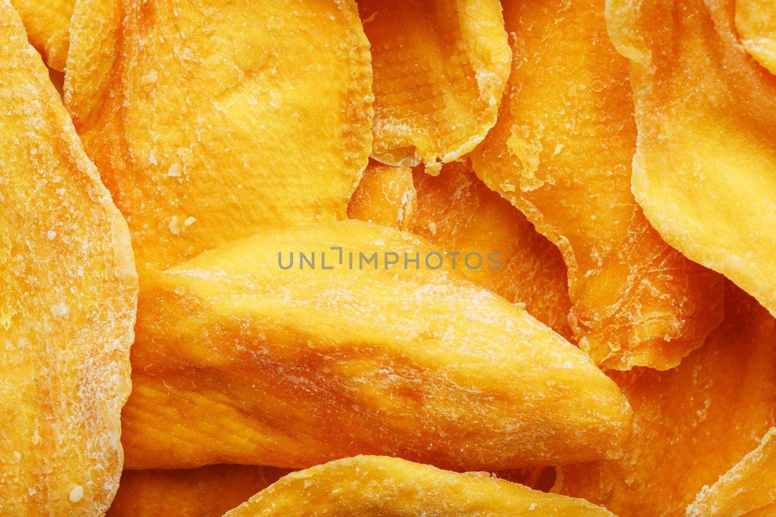 Dried sweet mango fruit slices as textural orange background in full screen