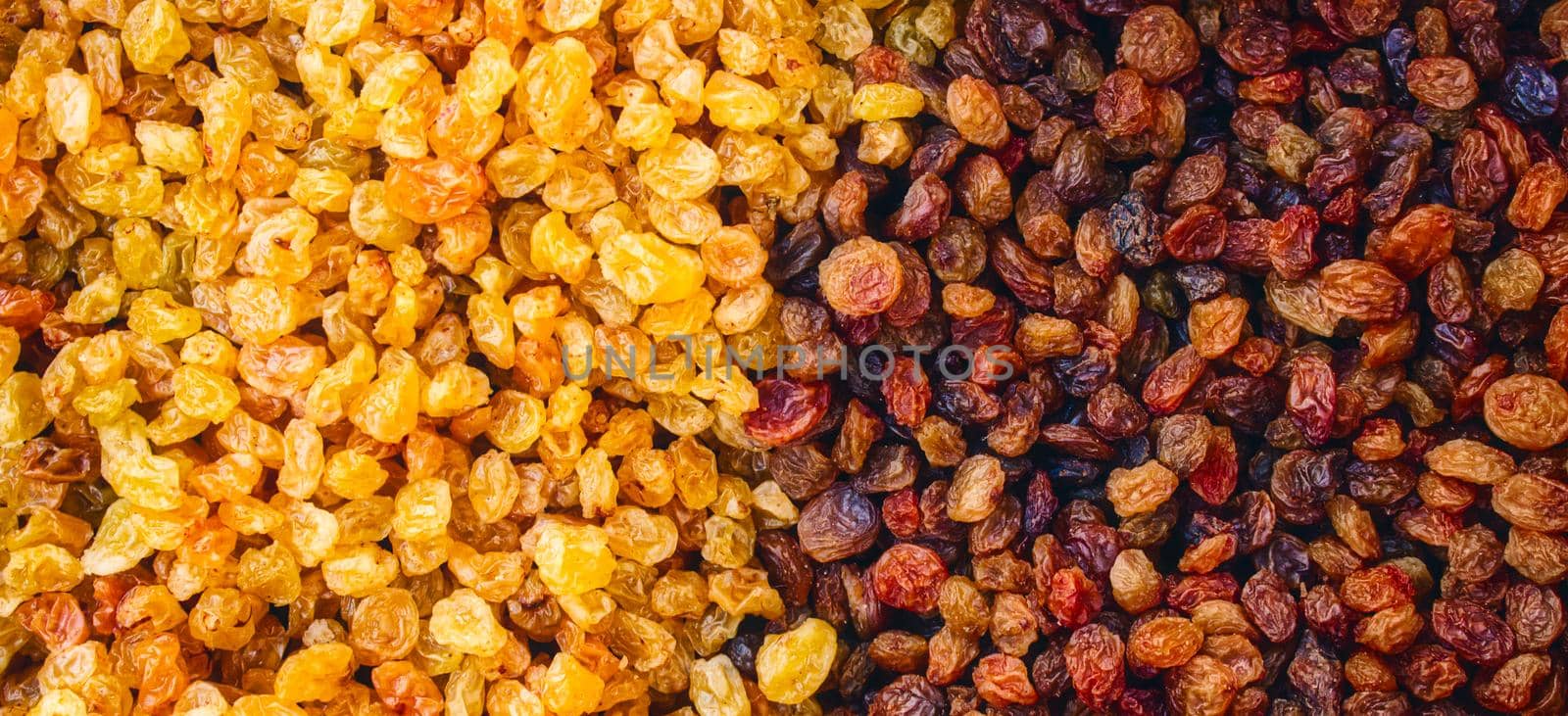 Raisins from white and black grapes forming a multi colored abstract texture background