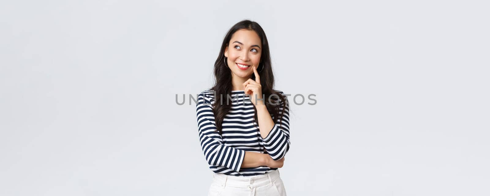 Lifestyle, people emotions and casual concept. Thoughtful stylish young woman smiling pleased, dreaming or imaging perfect plan, have interesting idea, thinking and looking upper left corner.