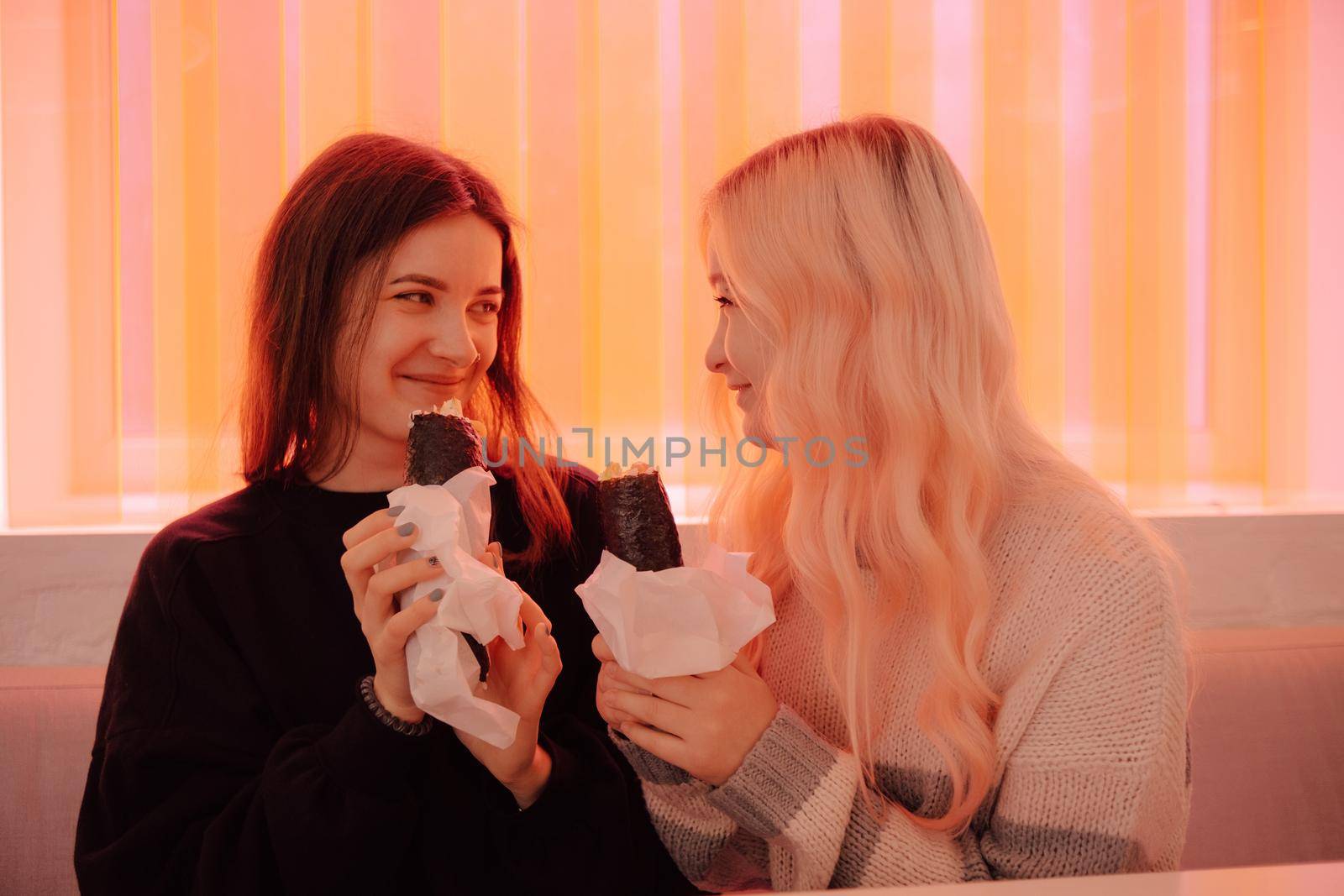 LGBT Lesbian couple eat sushi rolls in asian cafe with red light