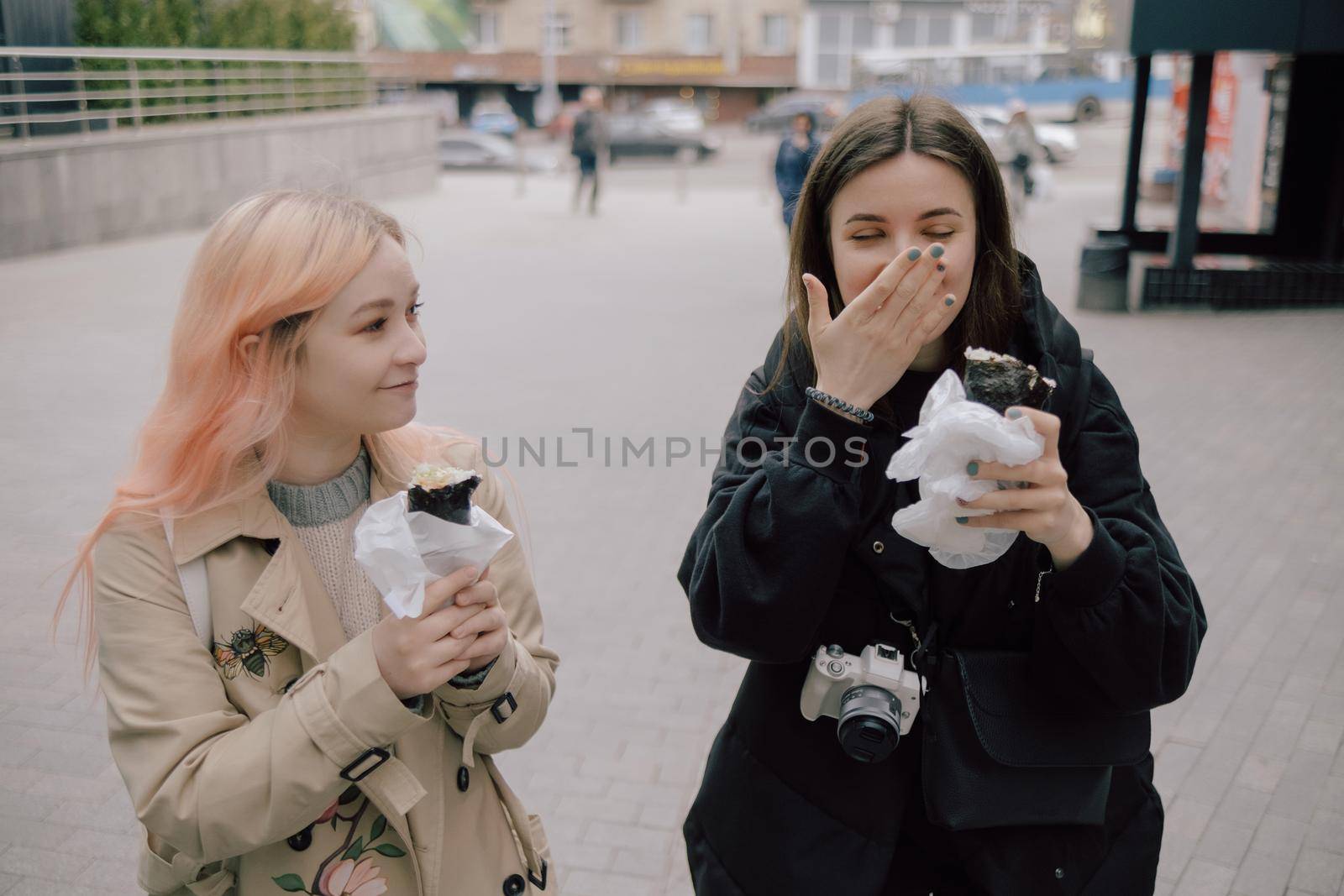LGBT Lesbian couple eat sushi rolls on the walk asian cafe. street food by Symonenko
